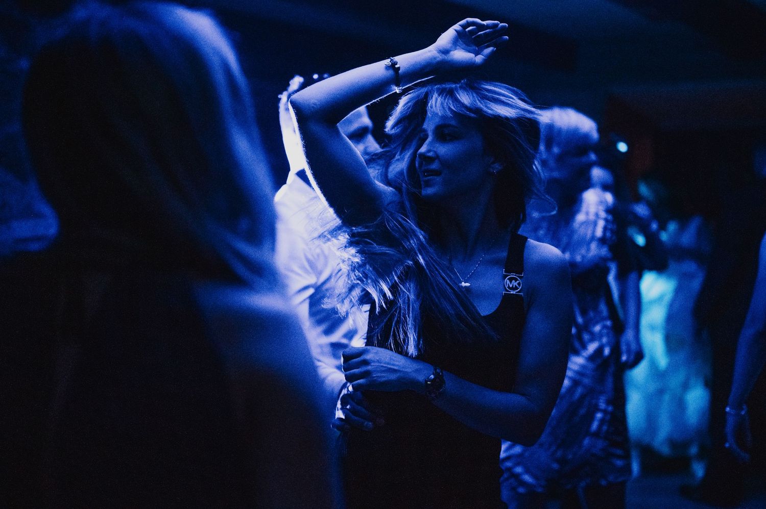 Woman dancing at a wedding reception bathed in blue atmospheric lighting.