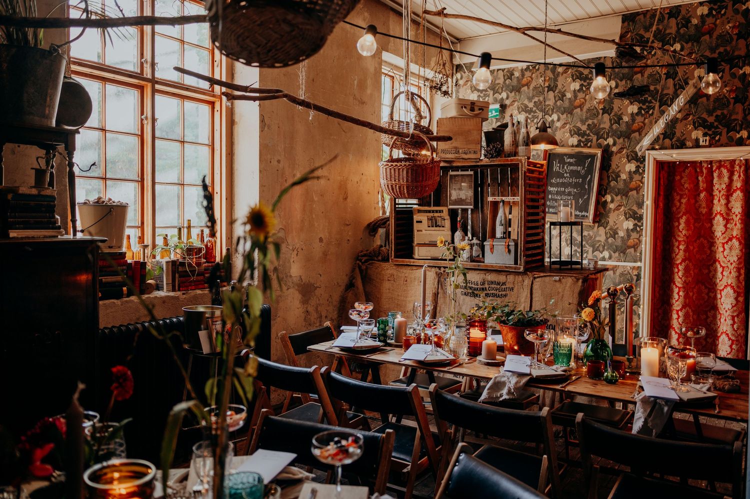 Eclectic bohemian wedding reception venue interior with string lights, tables, and colorful decor.