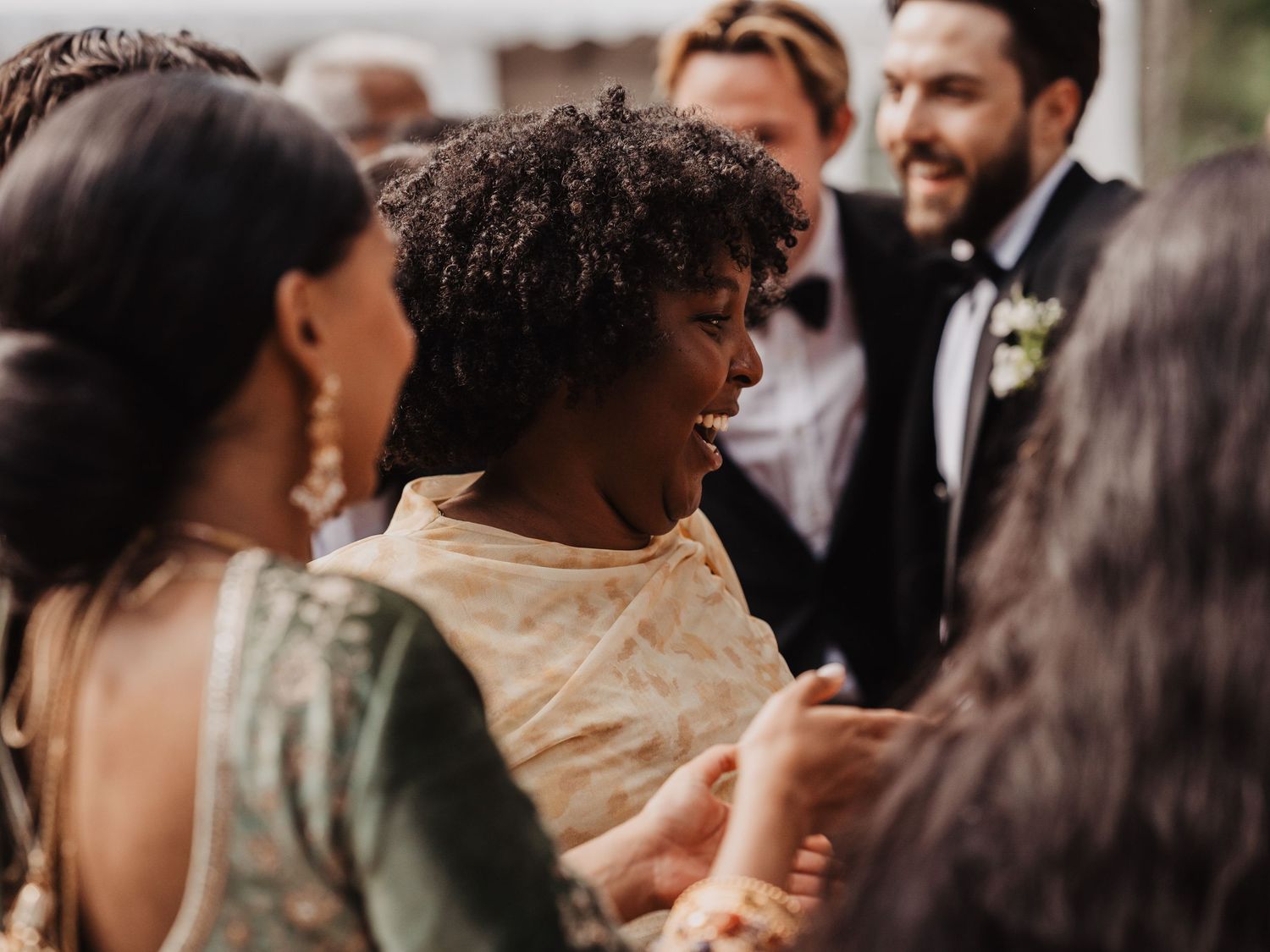 Diverse group of elegantly dressed guests socializing at an outdoor wedding celebration.
