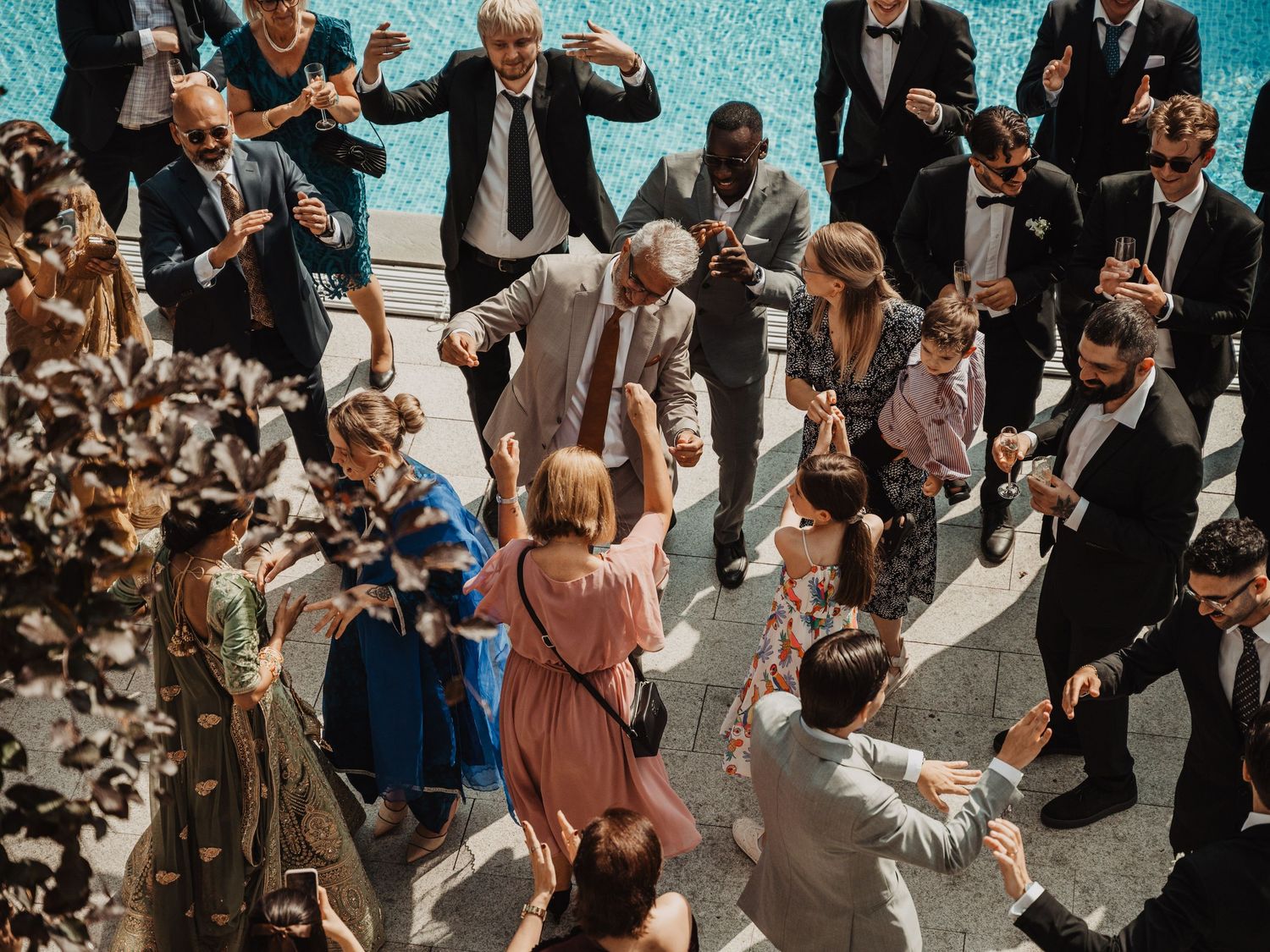 Aerial view of elegantly dressed wedding guests dancing and celebrating outdoors at a festive reception.