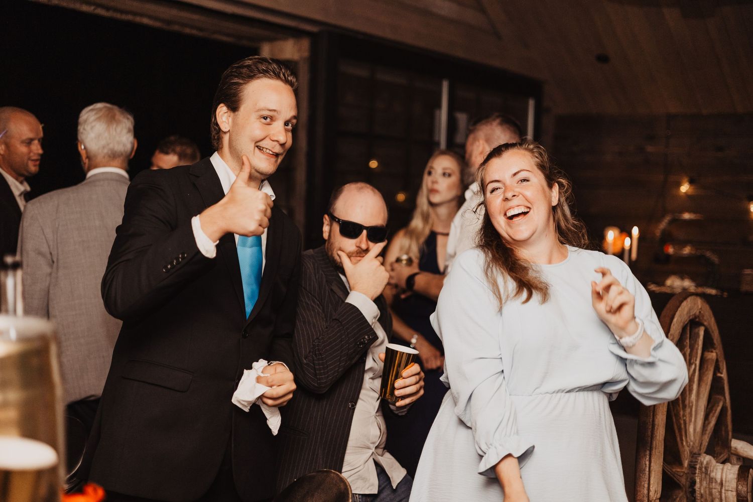 Guests laughing and dancing at a rustic wedding reception in a barn venue.