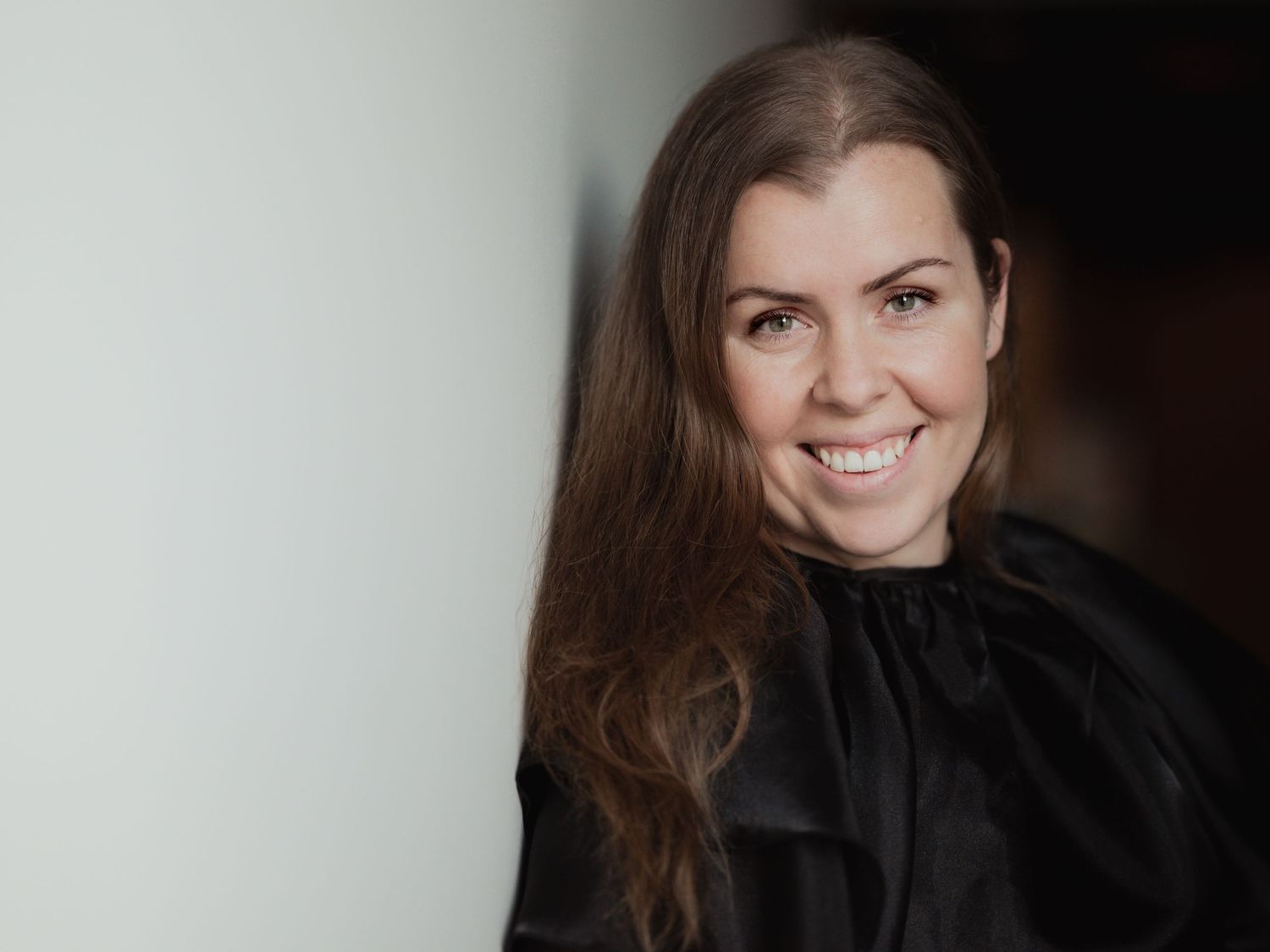 Professional female wedding photographer smiling in black outfit portrait photo.