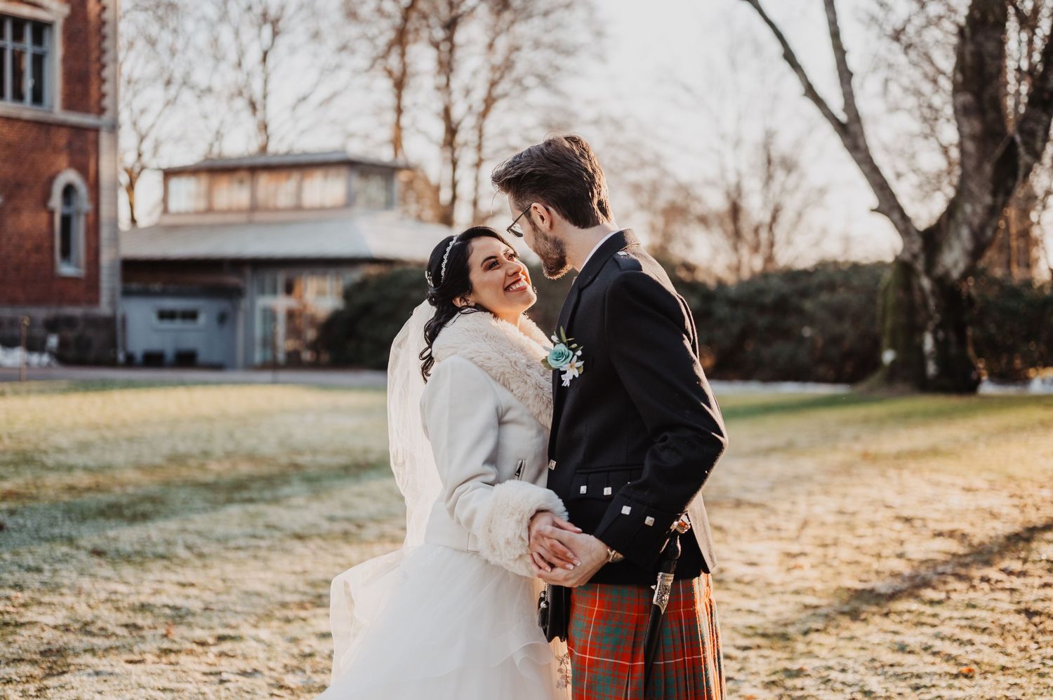 Happy couple share a tender moment laughing together on frosty winter wedding day outdoors.