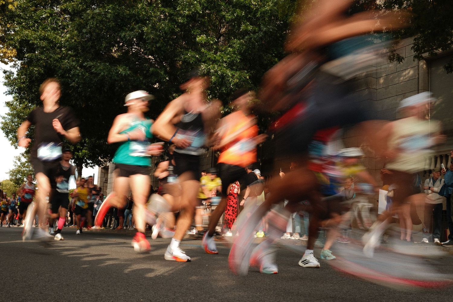 Motion blur of marathon runners racing past a stone wall.