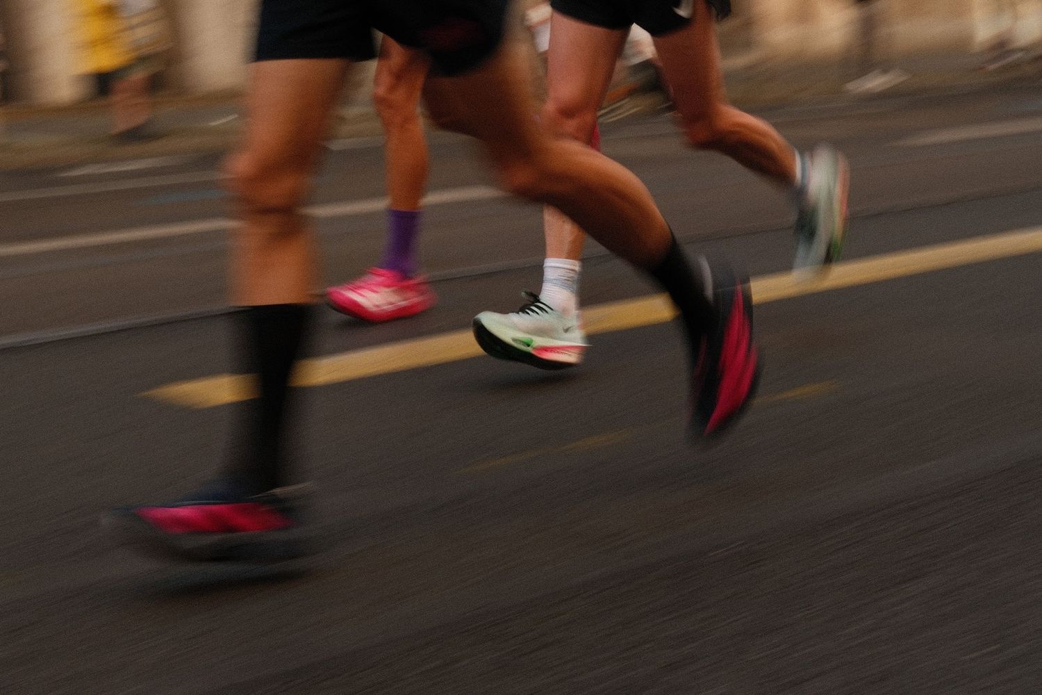 Close-up view of runners' feet in athletic shoes racing on an asphalt road during a marathon event.