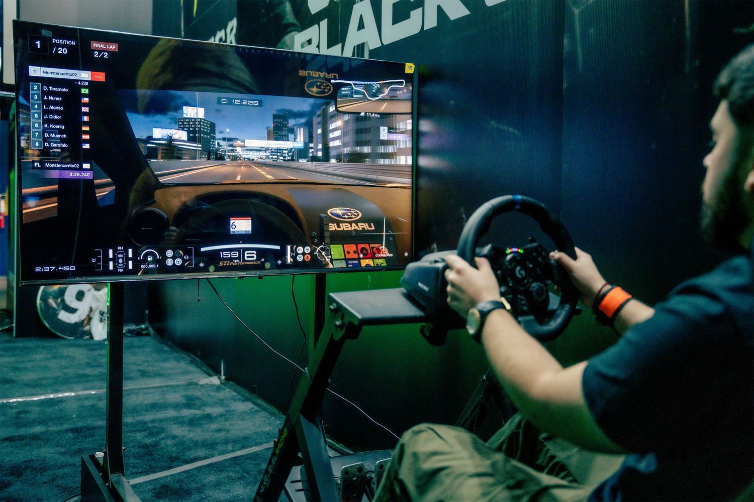 Professional esports players compete in a tournament with multiple gaming setups and monitors visible on stage.