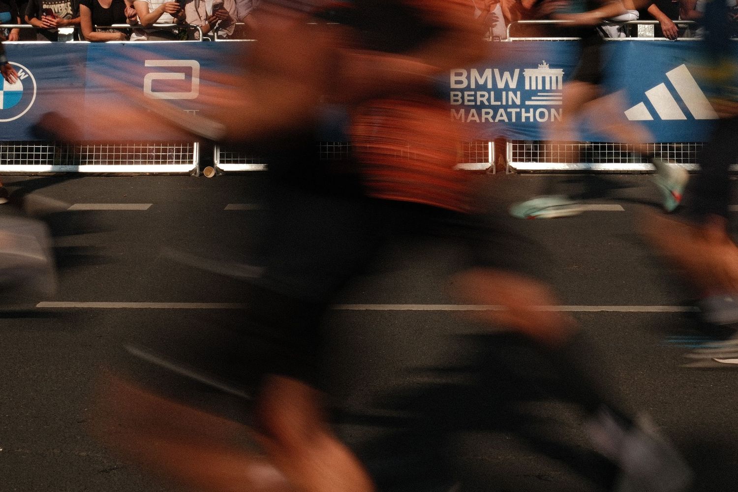 Motion blurred runners compete in the Berlin marathon with race banners visible in the background.