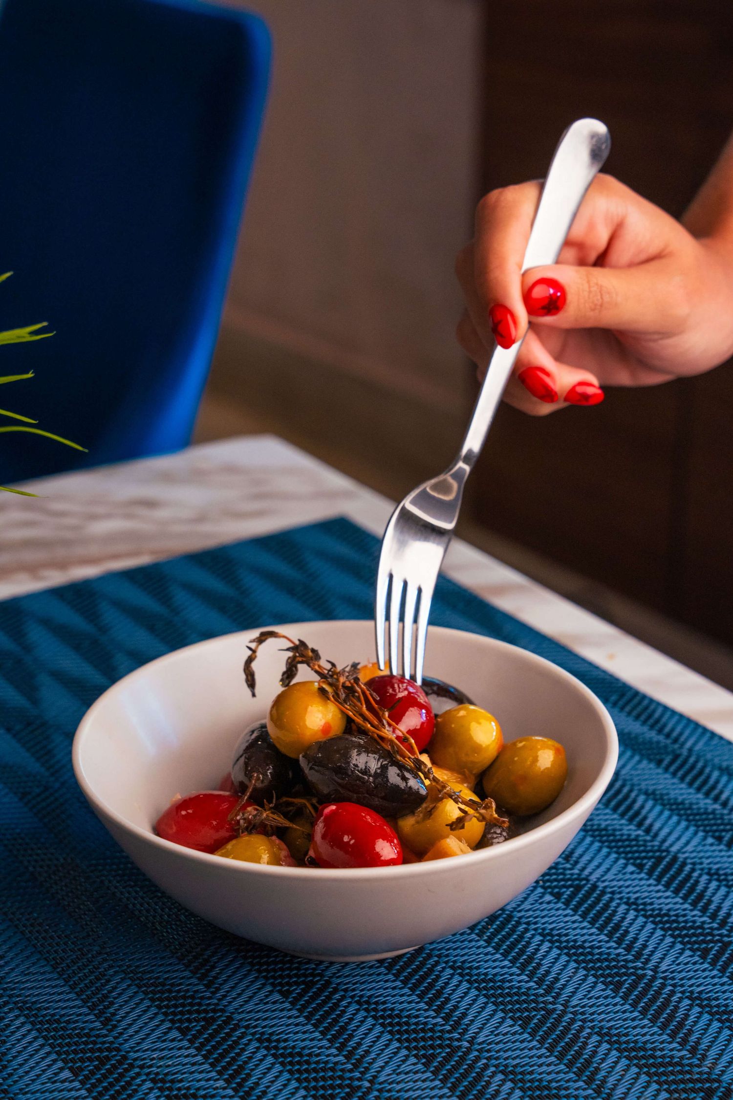 Small roasted potatoes and cherry tomatoes being served in a white bowl with a silver fork.