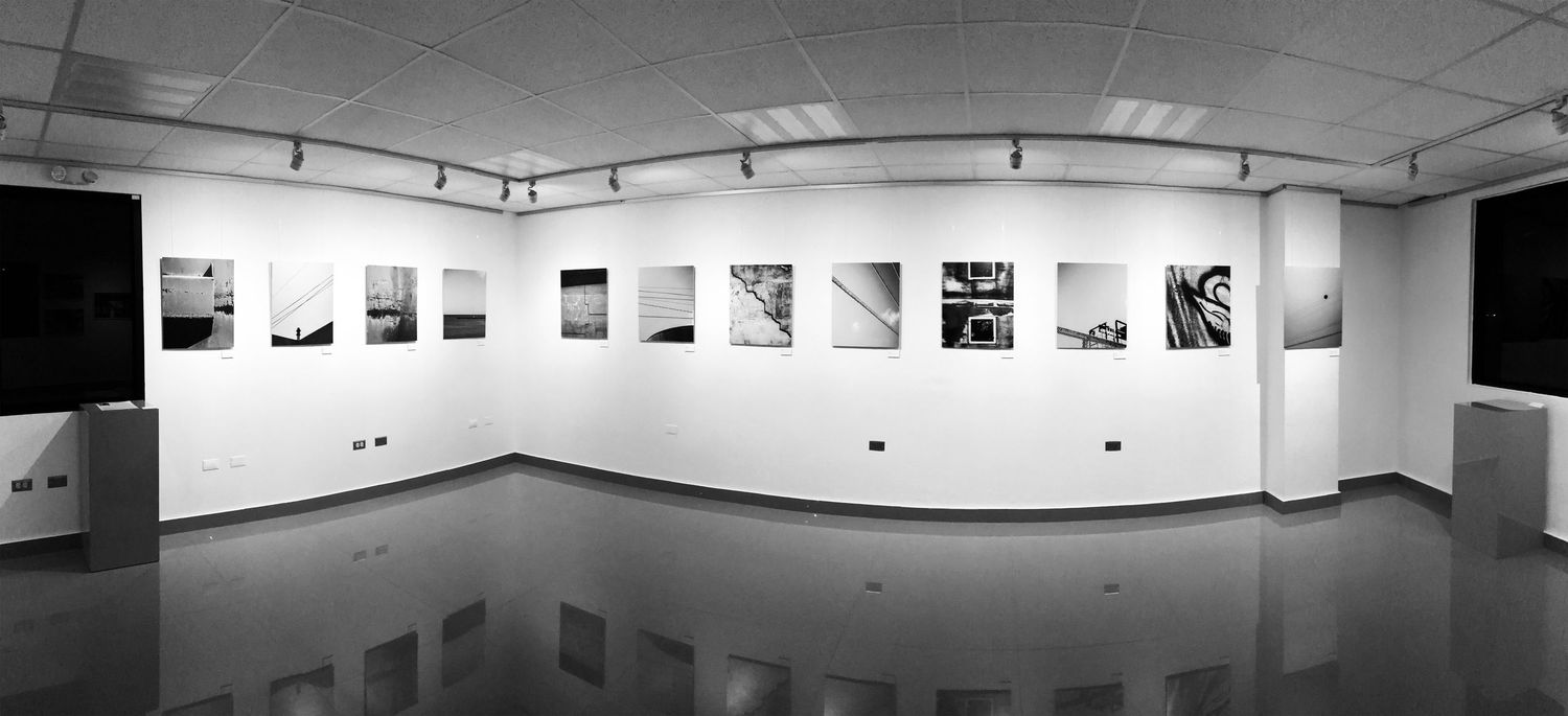 Panoramic view of a minimalist gallery space with photographs mounted on white walls.