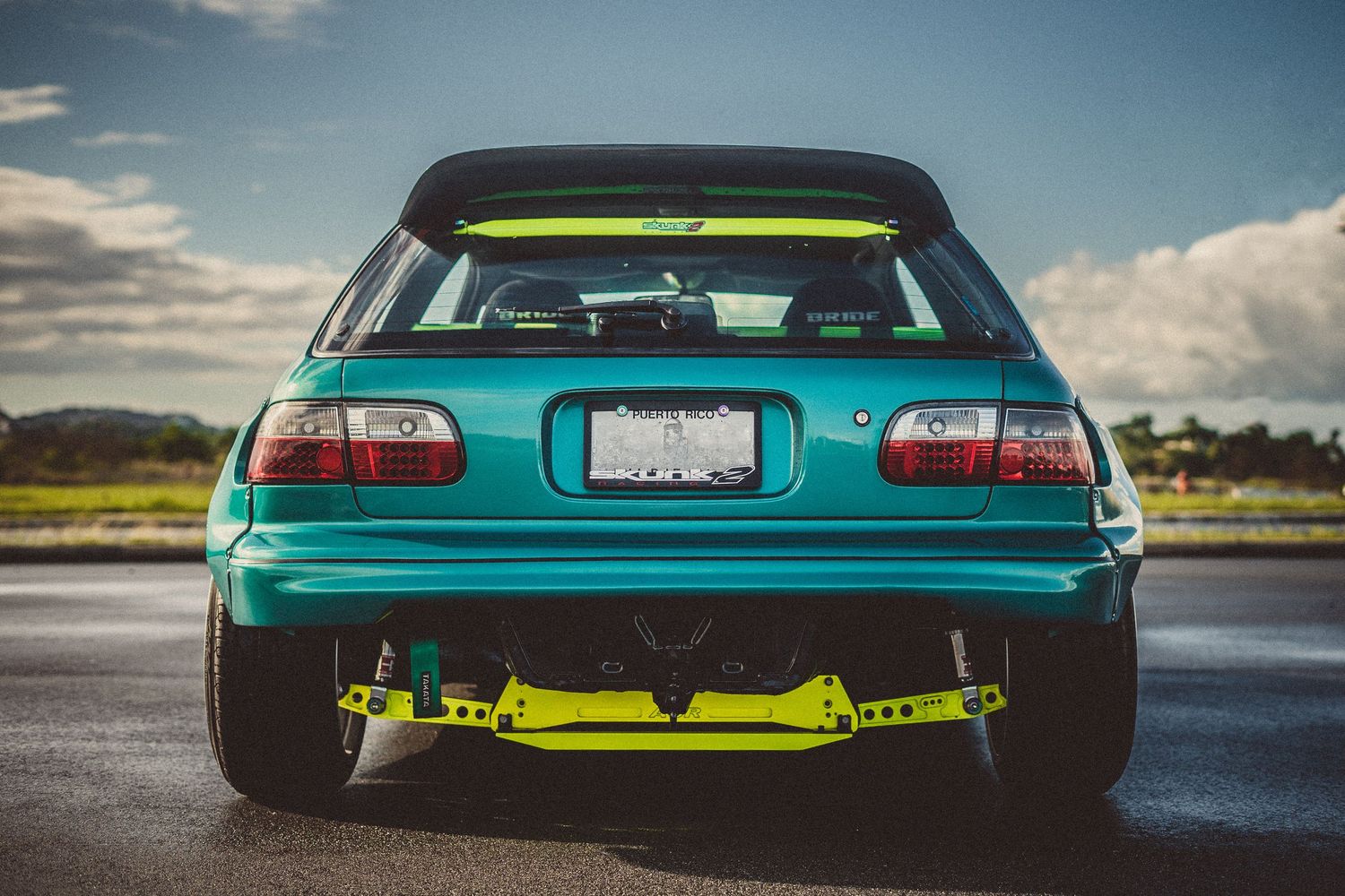 Low profile shots of a custom turquoise sports car showing its sleek side profile and rear design.