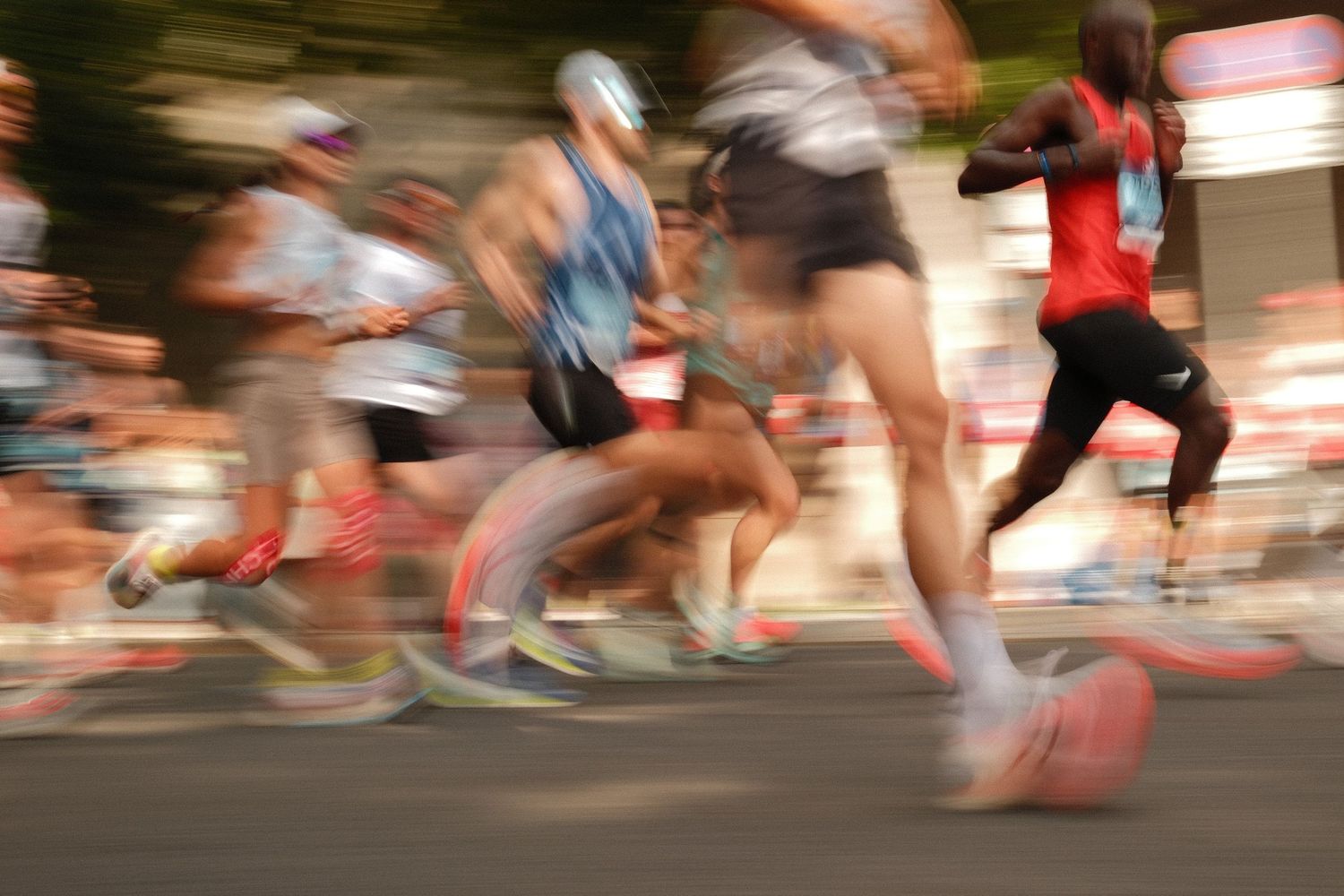 Motion-blurred legs of marathon runners racing on a street during a competitive event.