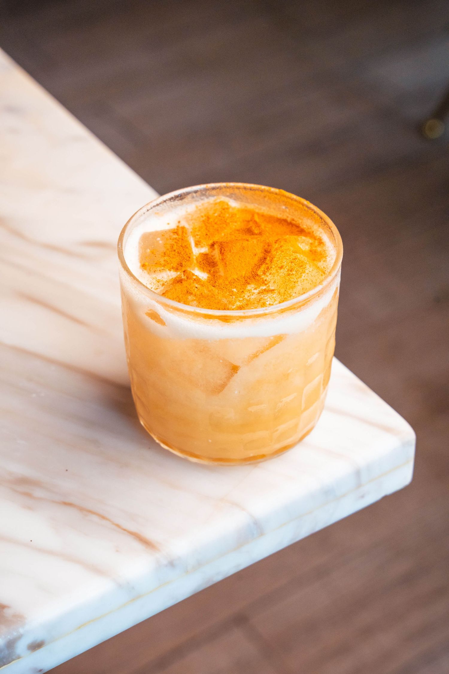 Creamy orange-colored mousse or dessert served in a glass ramekin on marble surface.