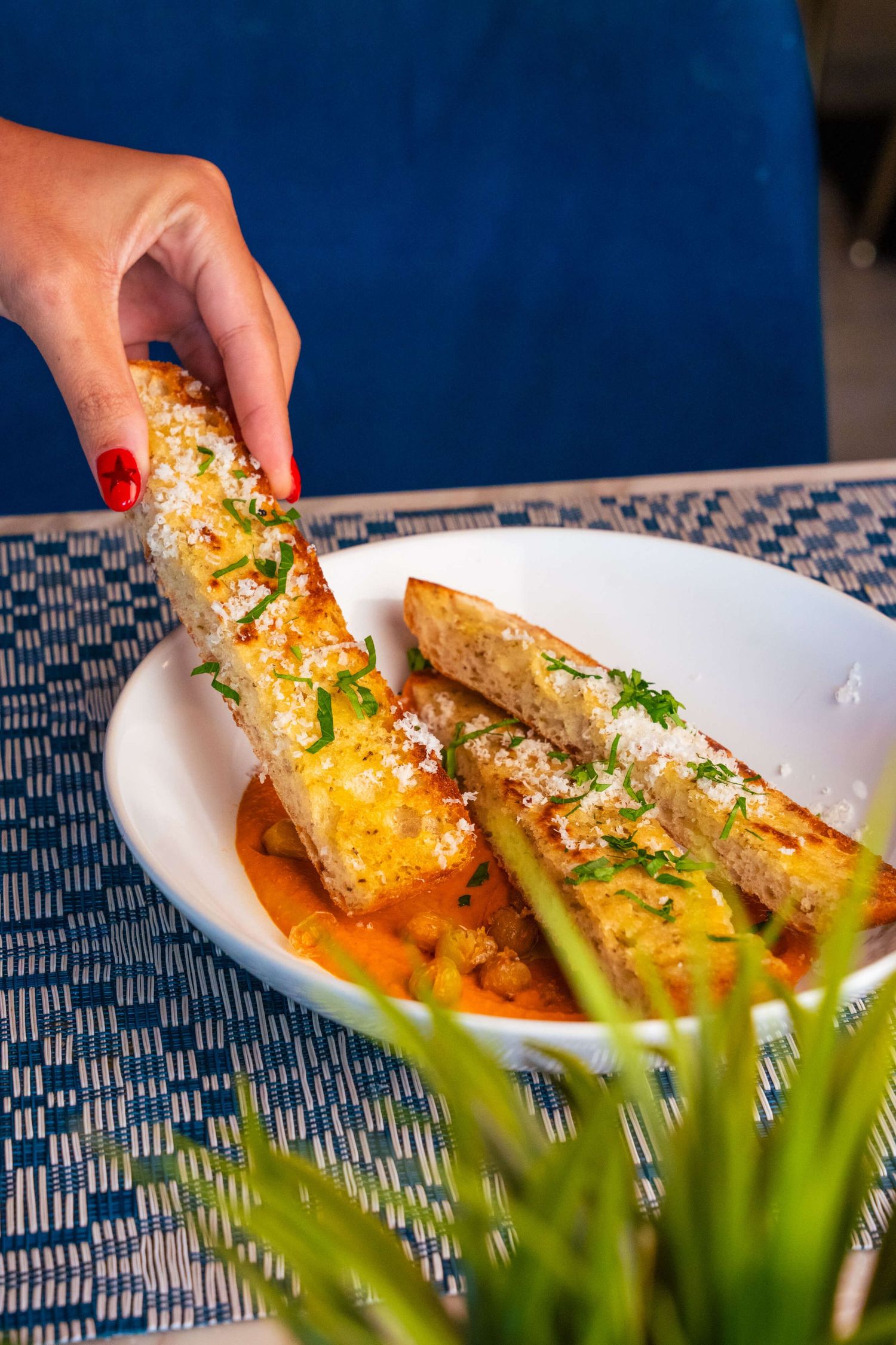 Crispy breaded fish fillets plated on orange sauce with fresh herbs and garnish.