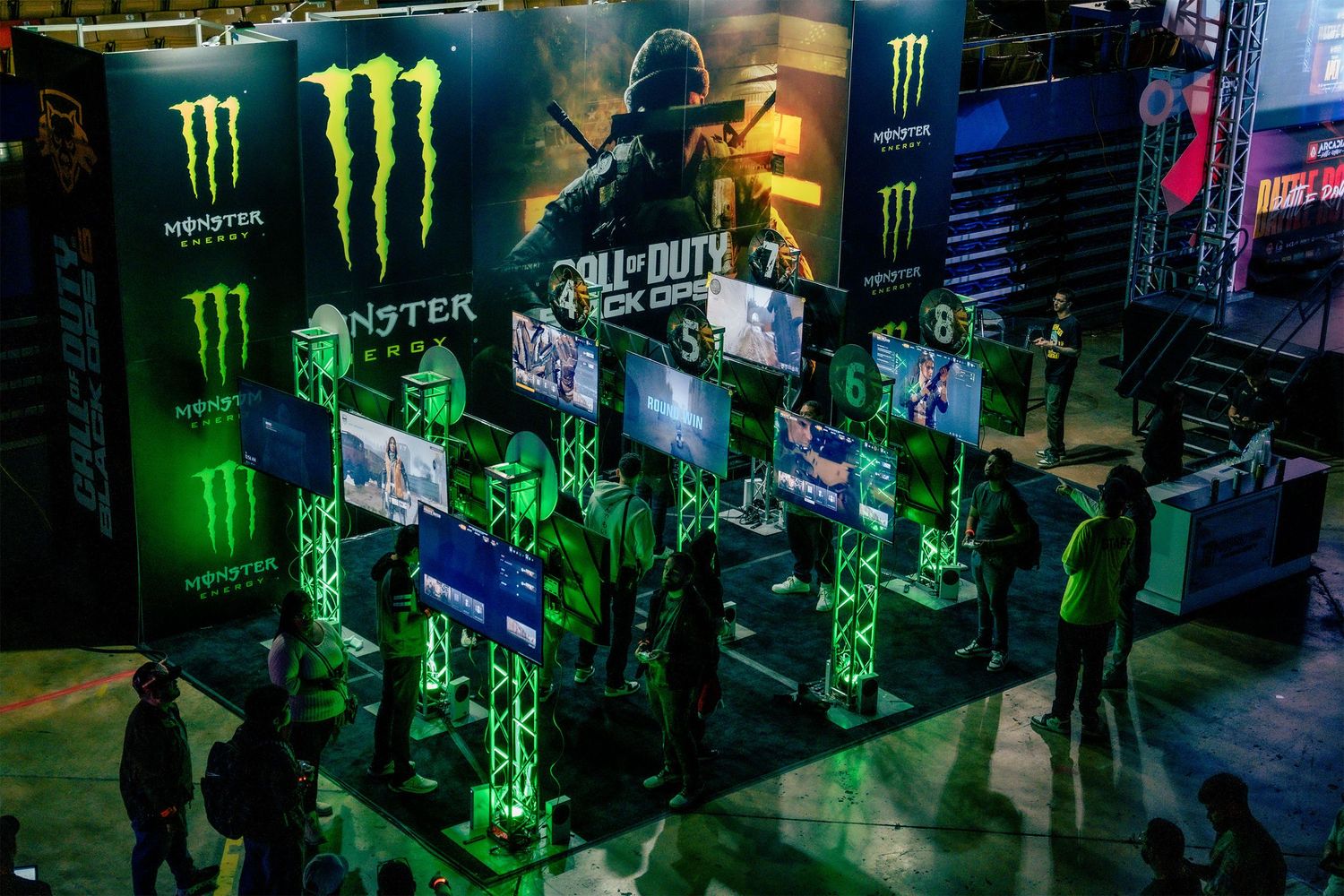Monster Energy branded gaming event space with neon green lighting and multiple gaming stations.