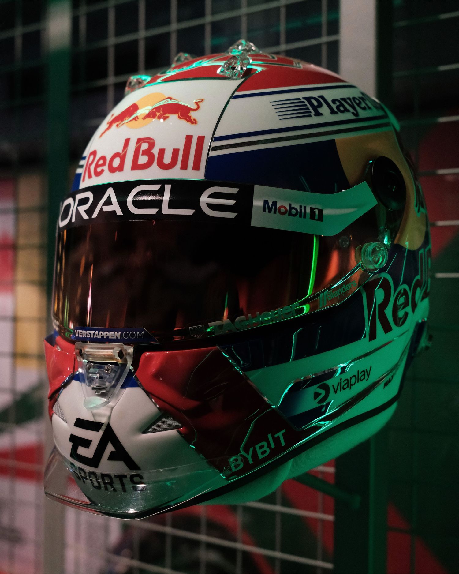 Row of Red Bull Formula 1 Max Verstappen racing helmets with green and red accents on display.