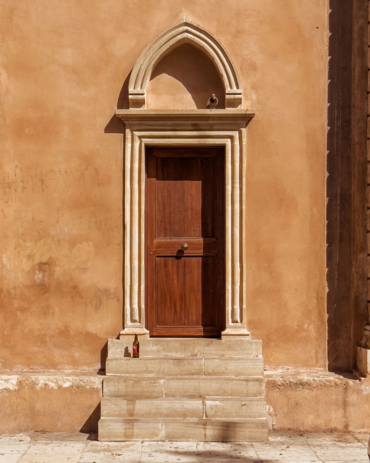 Weathered stone archways and doorways on terracotta colored building facade.
