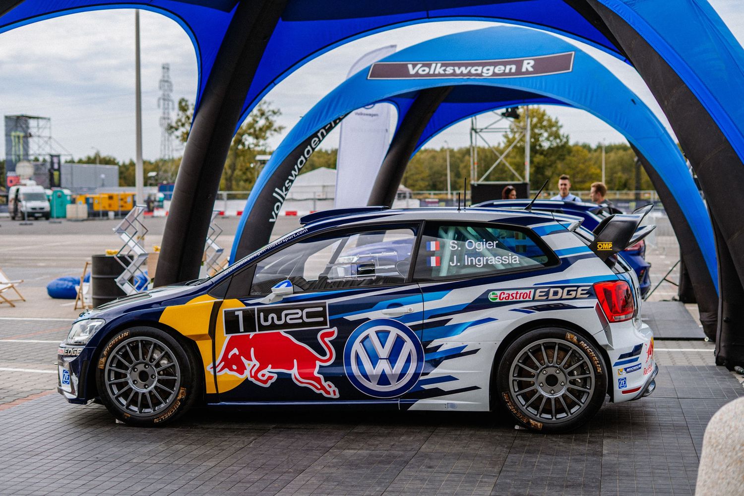 Rally cars under blue inflatable arches on a event.