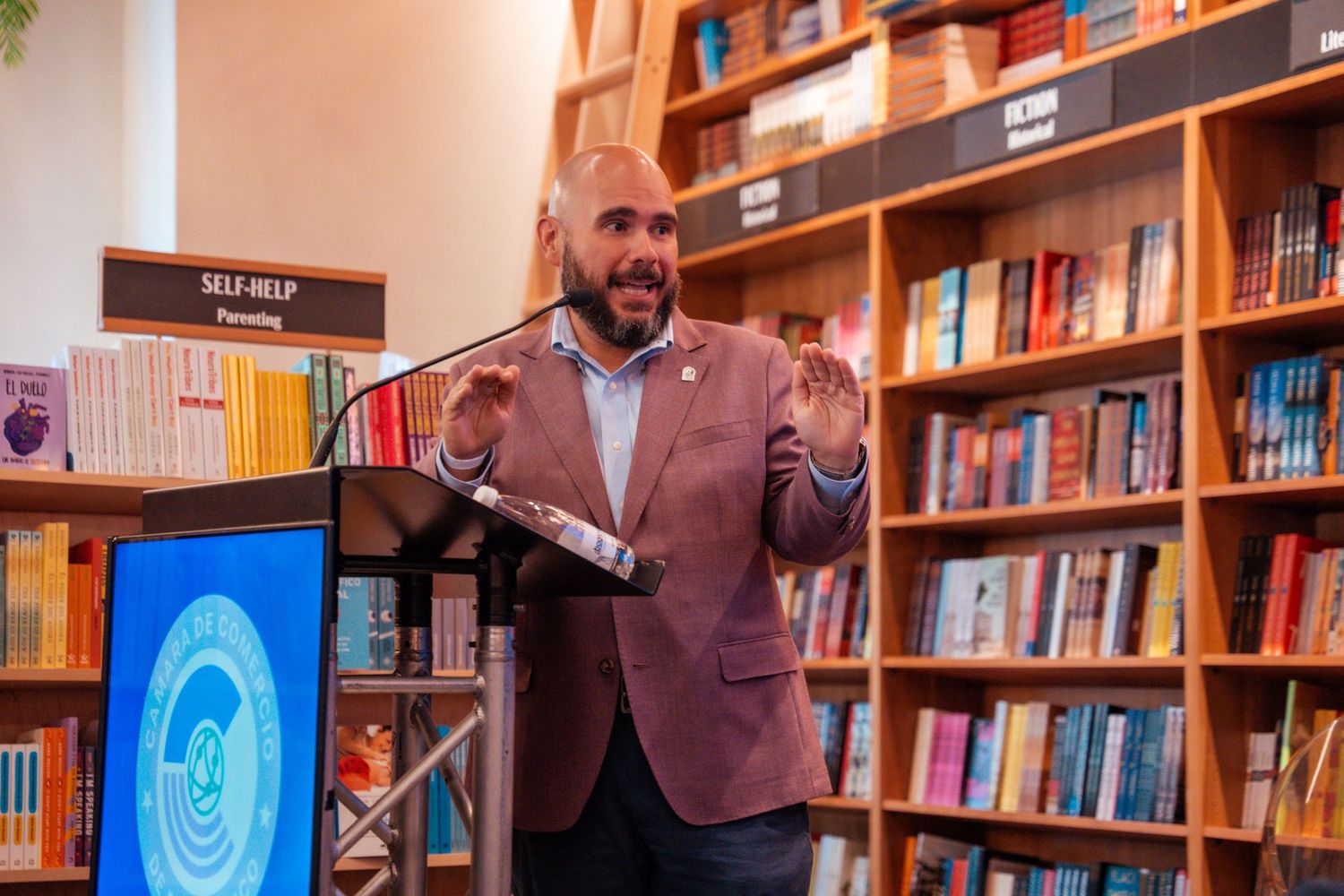 Business event in a bookstore with speakers seated in front of wooden shelves filled with books.