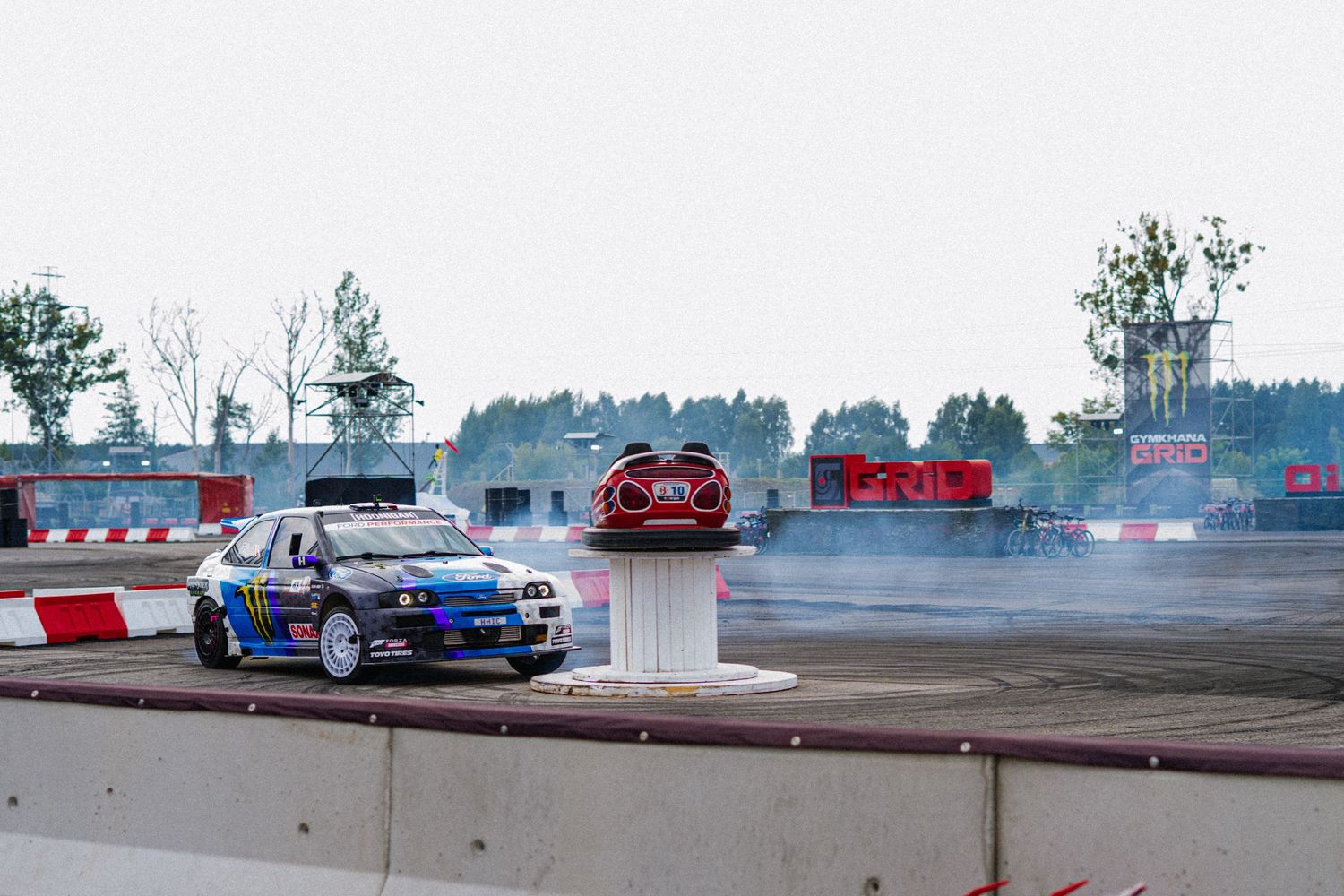 Drift car performing on a race track with smoke trails visible.