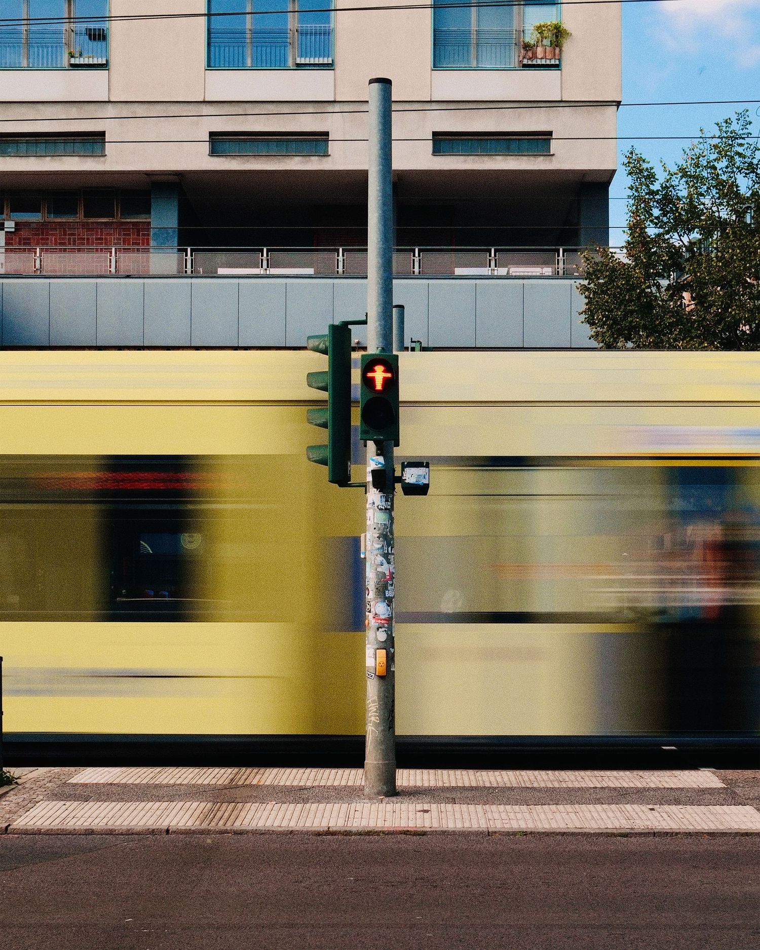Motion blur of a yellow train passing by modern office buildings in an urban setting.