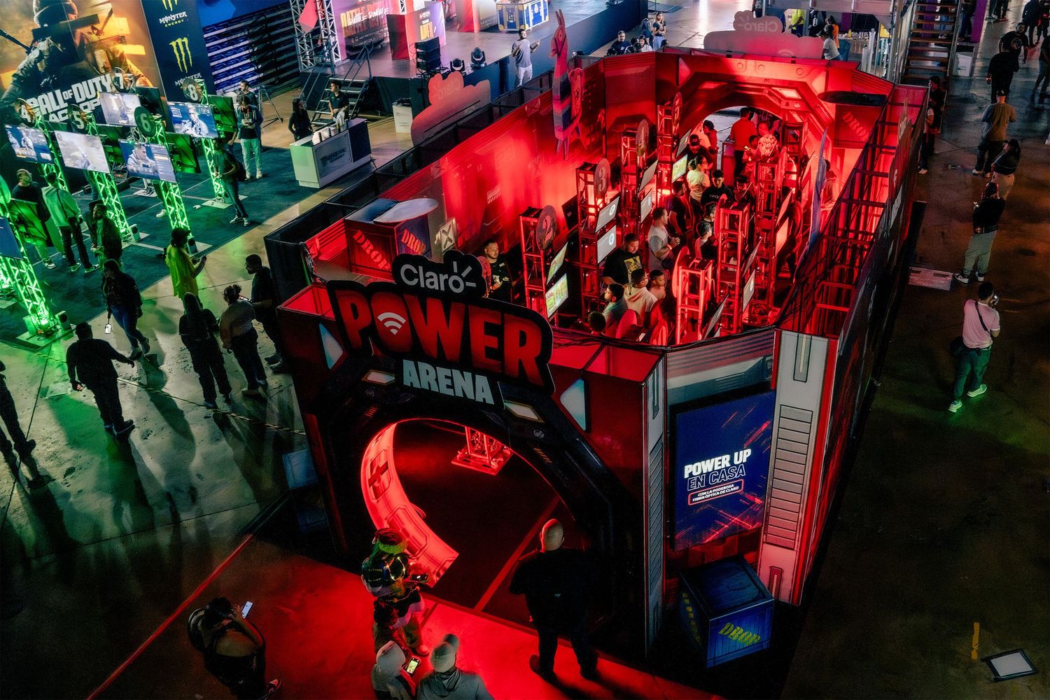 Esports gaming event with colorful red and green lighting illuminating players at computer stations.