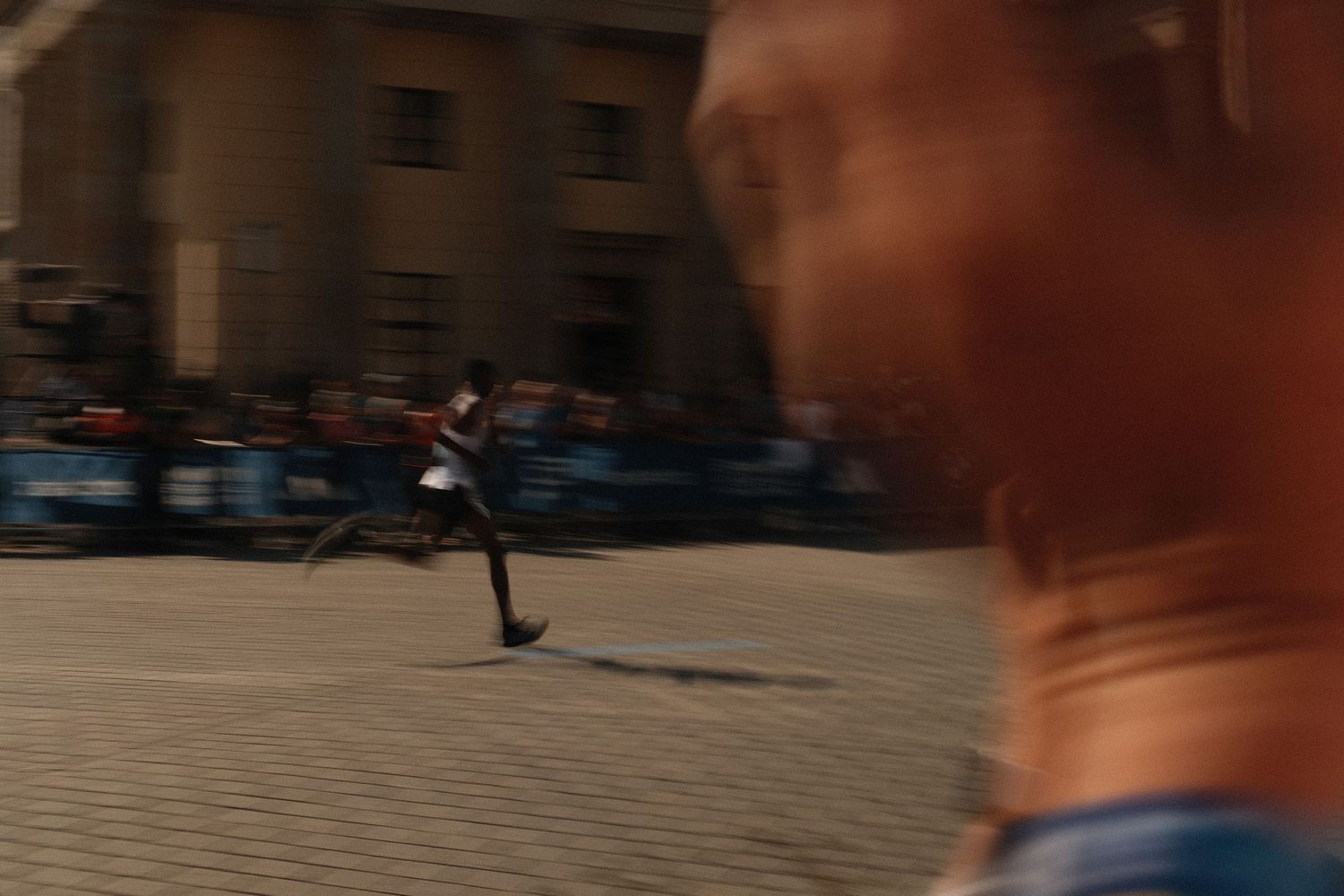 Runners' legs in motion blur against an urban backdrop during a marathon race.