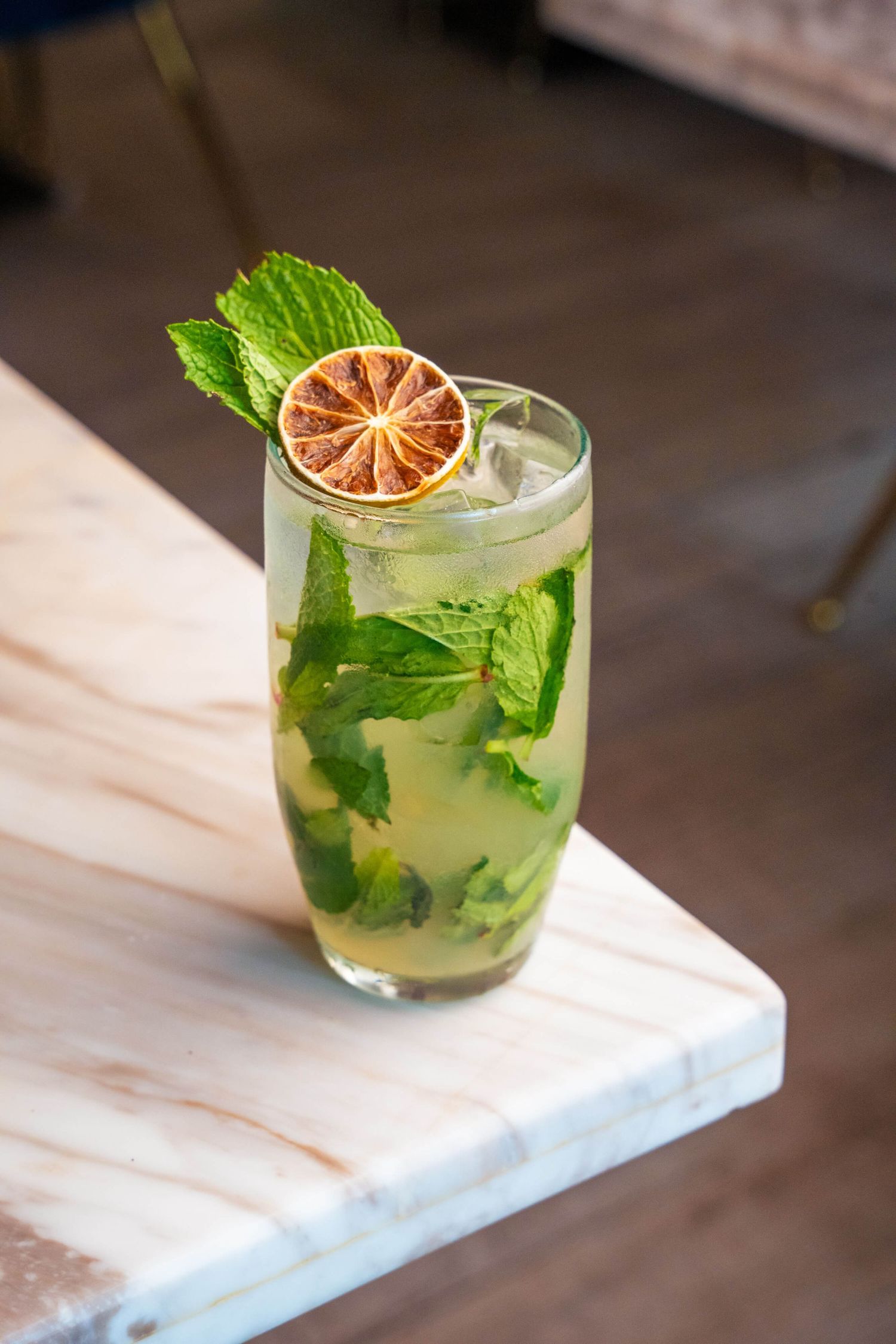 Refreshing mojito cocktail garnished with mint leaves and dried citrus slice.