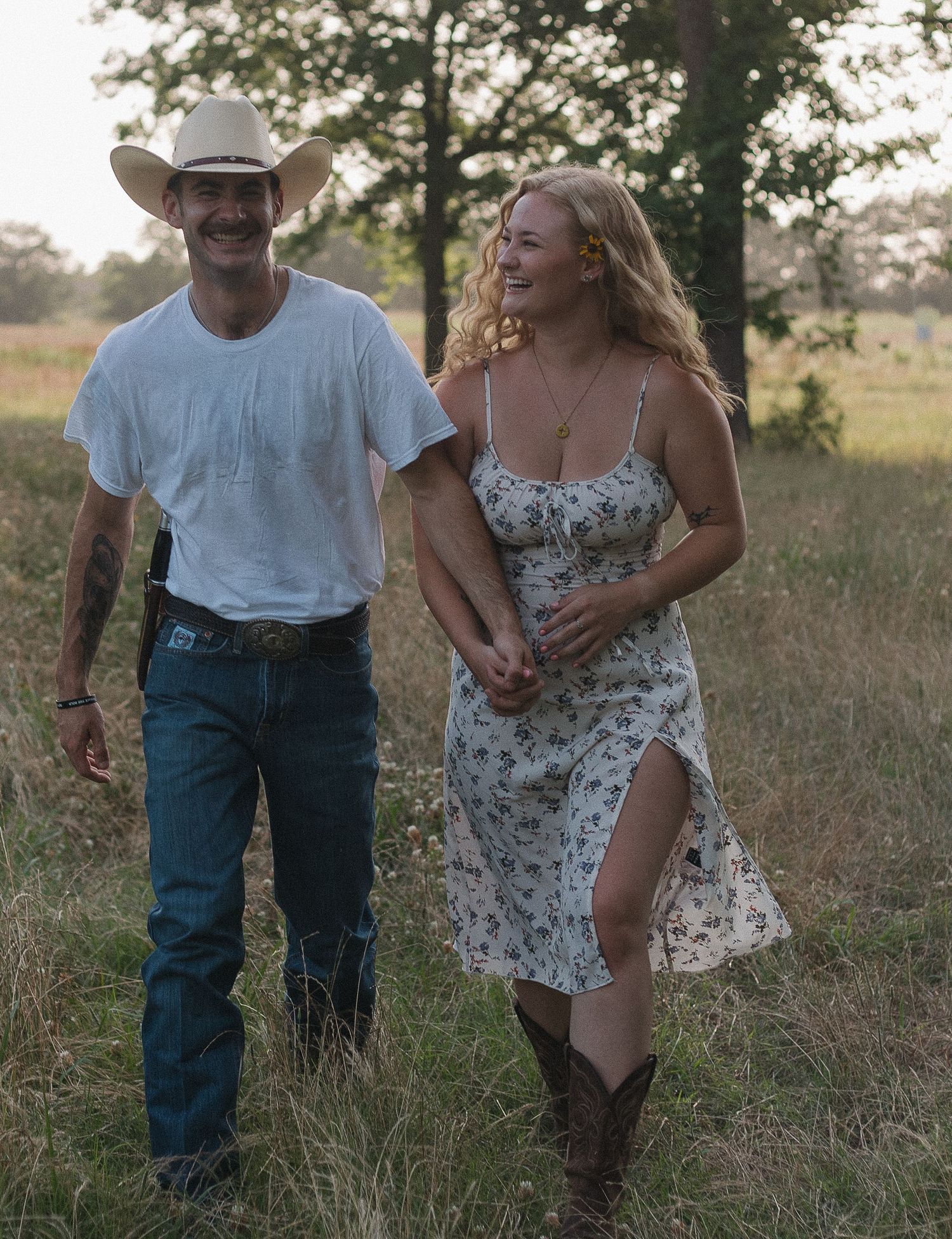 A couple walks through a sun-drenched meadow wearing casual country attire on a warm summer afternoon Gun Barrel City, Texas