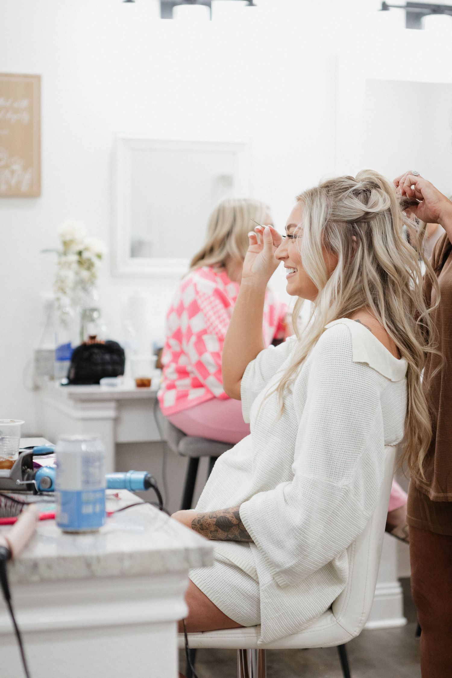 Getting ready in a bright salon with makeup and styling products scattered on white counter.
