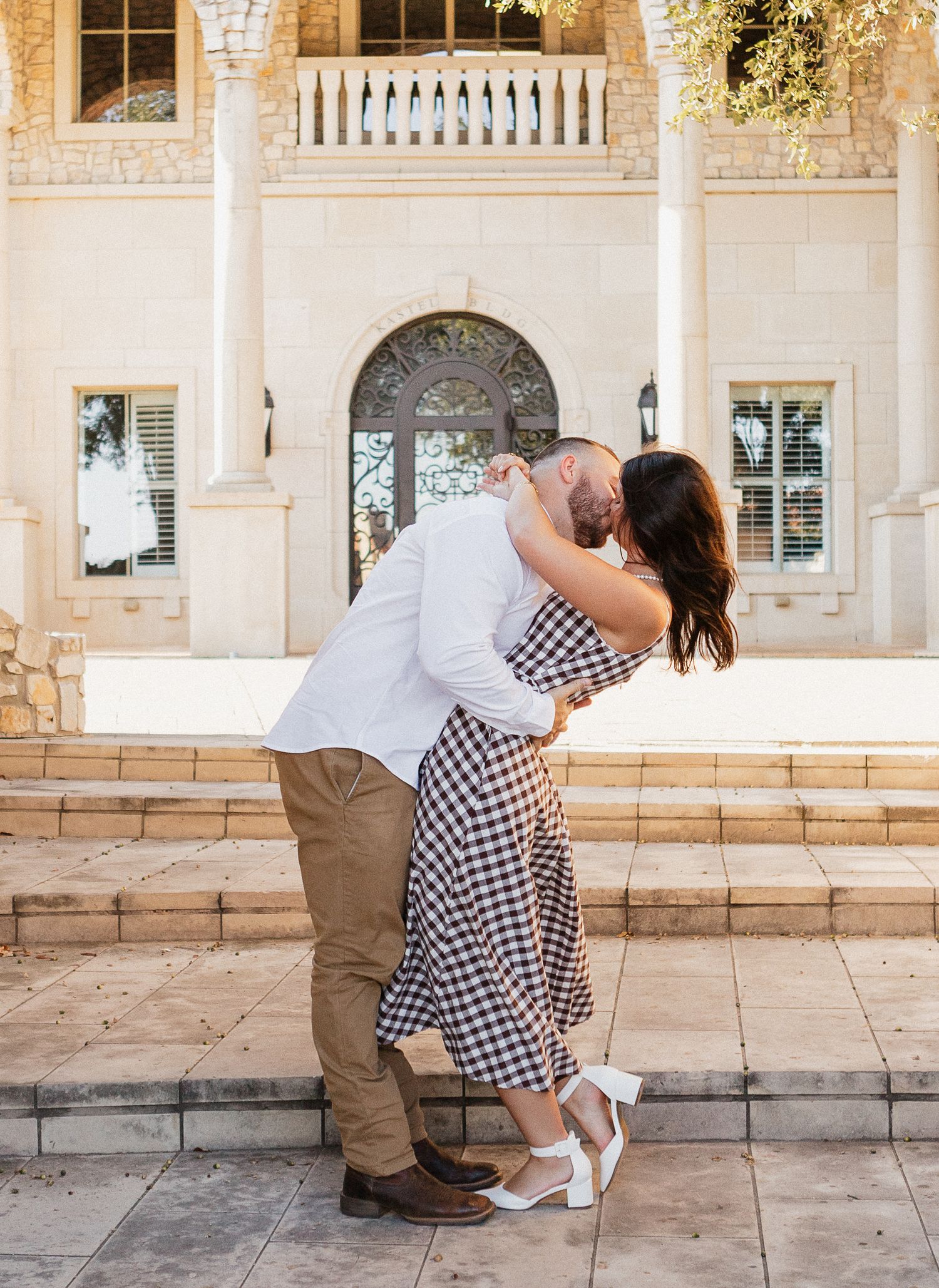 A romantic dance pose on a stone patio in front of a classic building facade.