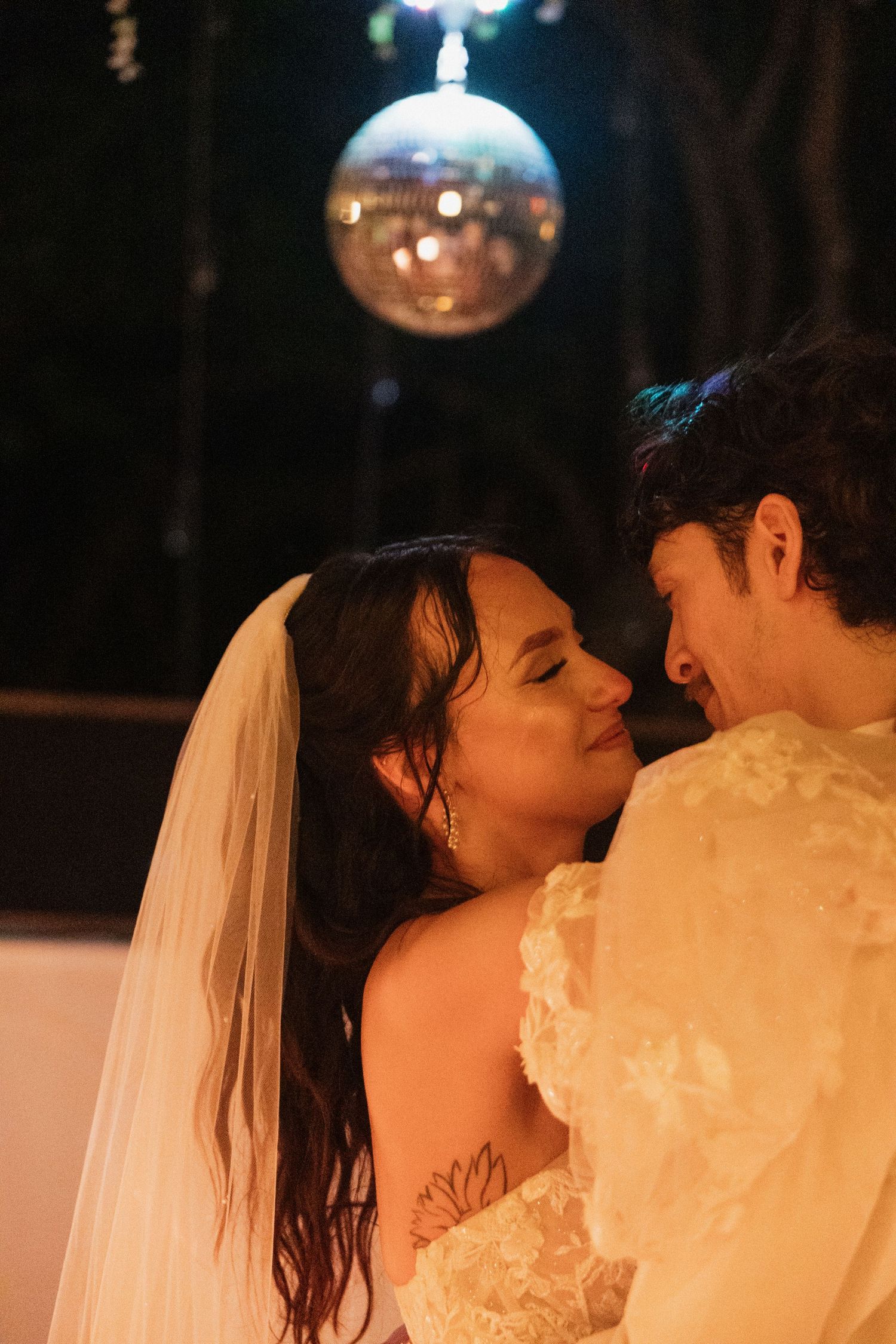 Bride and groom share a romantic moment under a glowing disco ball at their evening wedding reception.Caddo Mills Texas wedding photographer