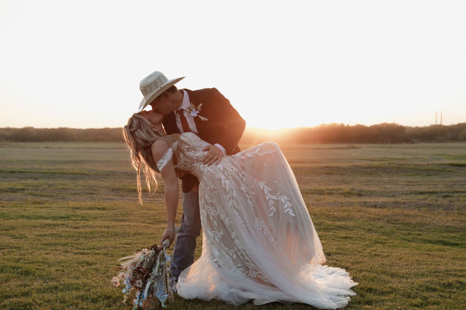 Couple sharing intimate moment in field during golden hour wedding photoshoot.