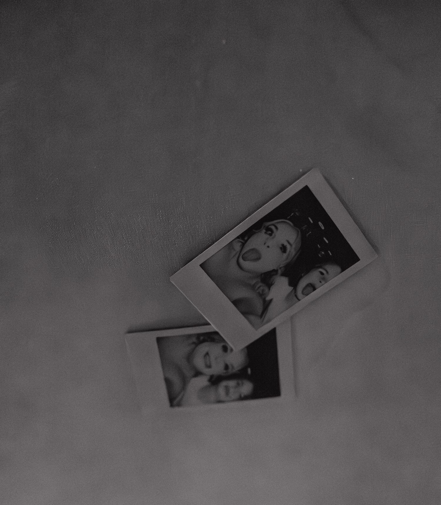Two black and white Polaroid photos of smiling friends captured in candid, joyful moments at a wedding celebration.