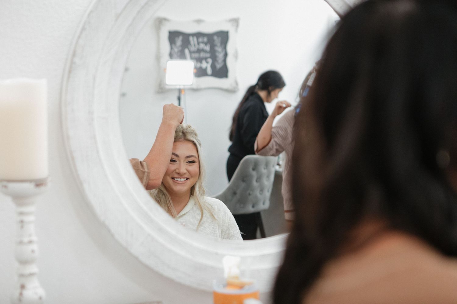 Reflection in round white mirror shows wedding preparation activities.