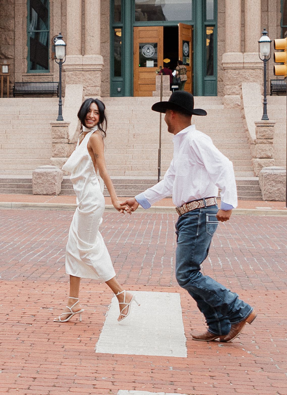 Dancing couple on brick paved courtyard in western attire.