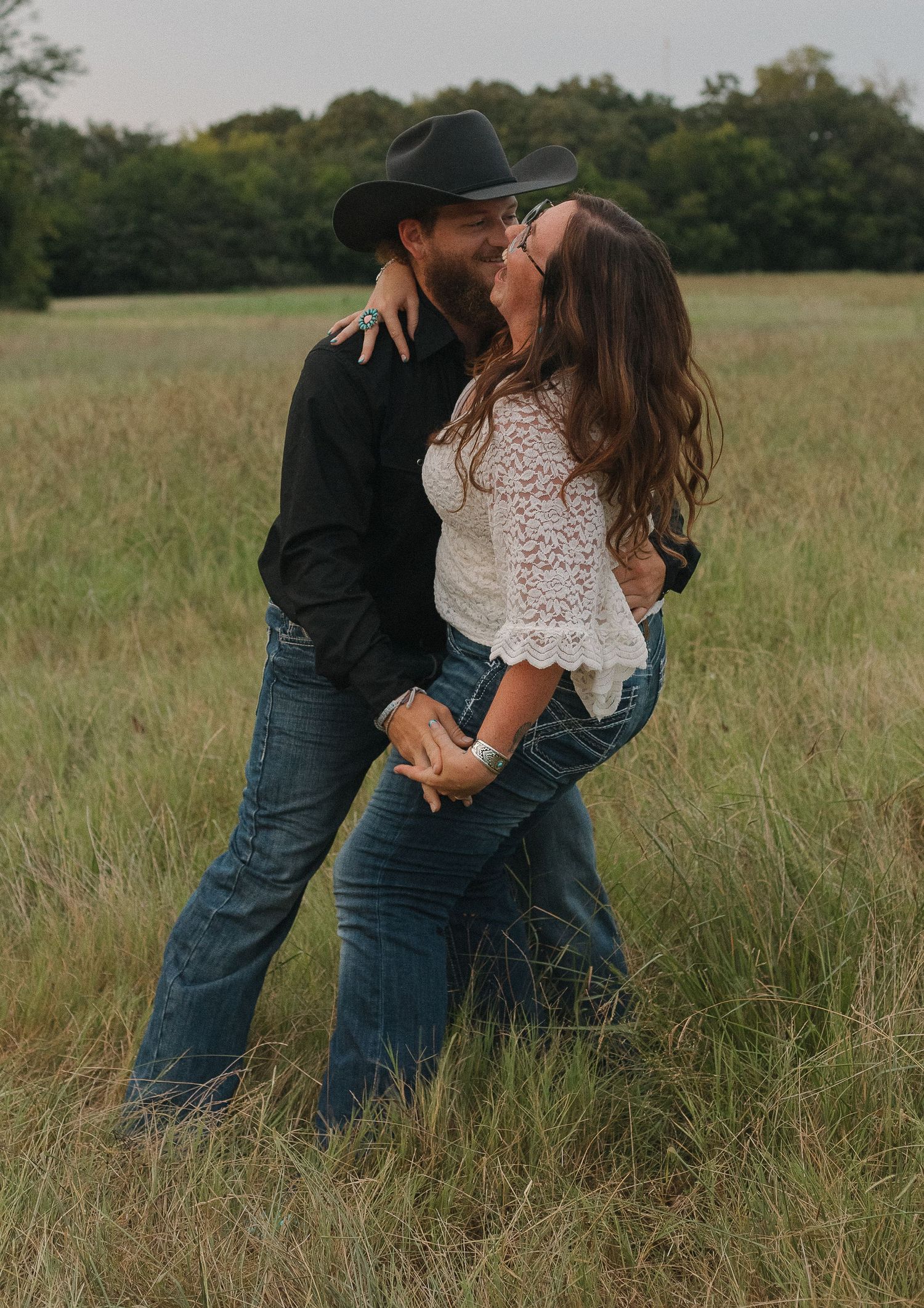 A couple embraces in a serene field of tall grass during an intimate outdoor photoshoot in Greenville, Texas