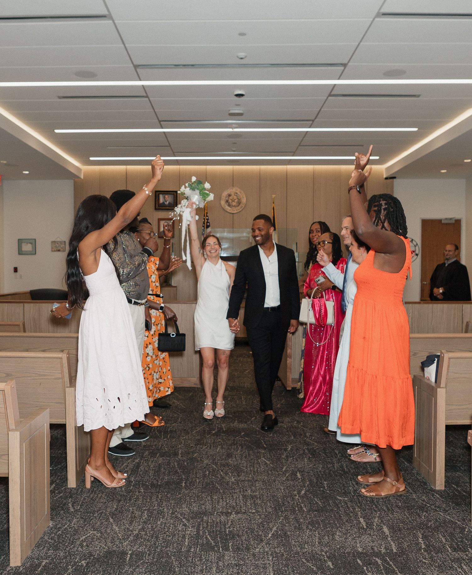 Wedding party dancing and celebrating in an indoor venue with carpeted floor.