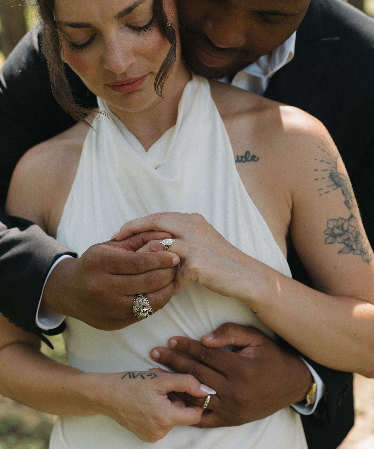 Close-up of hands exchanging wedding rings during outdoor ceremony.