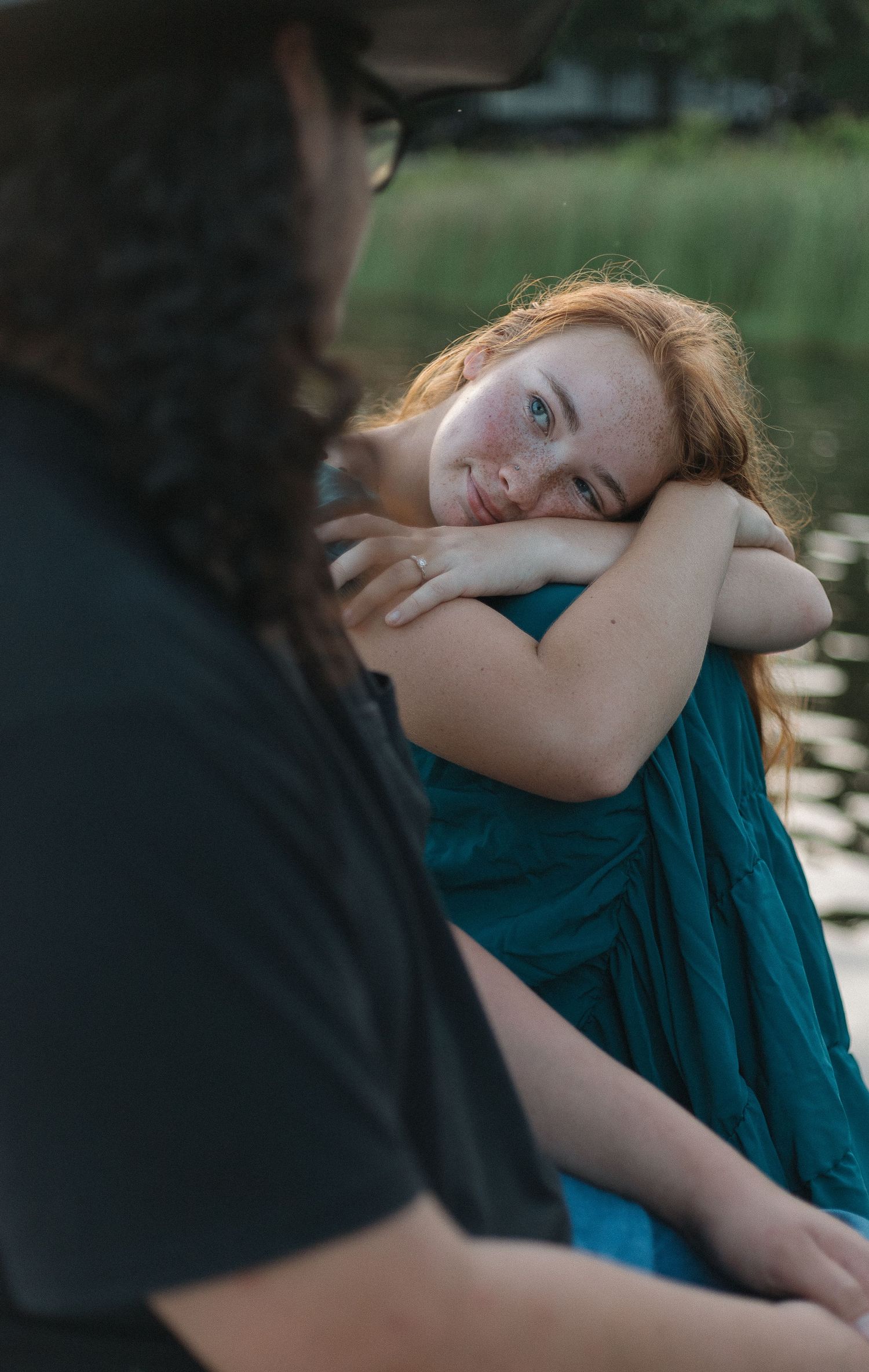 Two people having an intimate conversation outdoors, with one wearing a teal dress resting on their arms Gun Barrel City, Texas