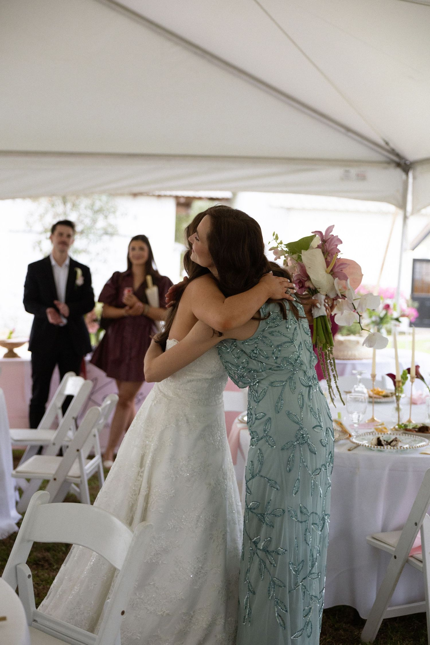 Wedding reception scene under white tent with tables and guests celebrating a special moment.