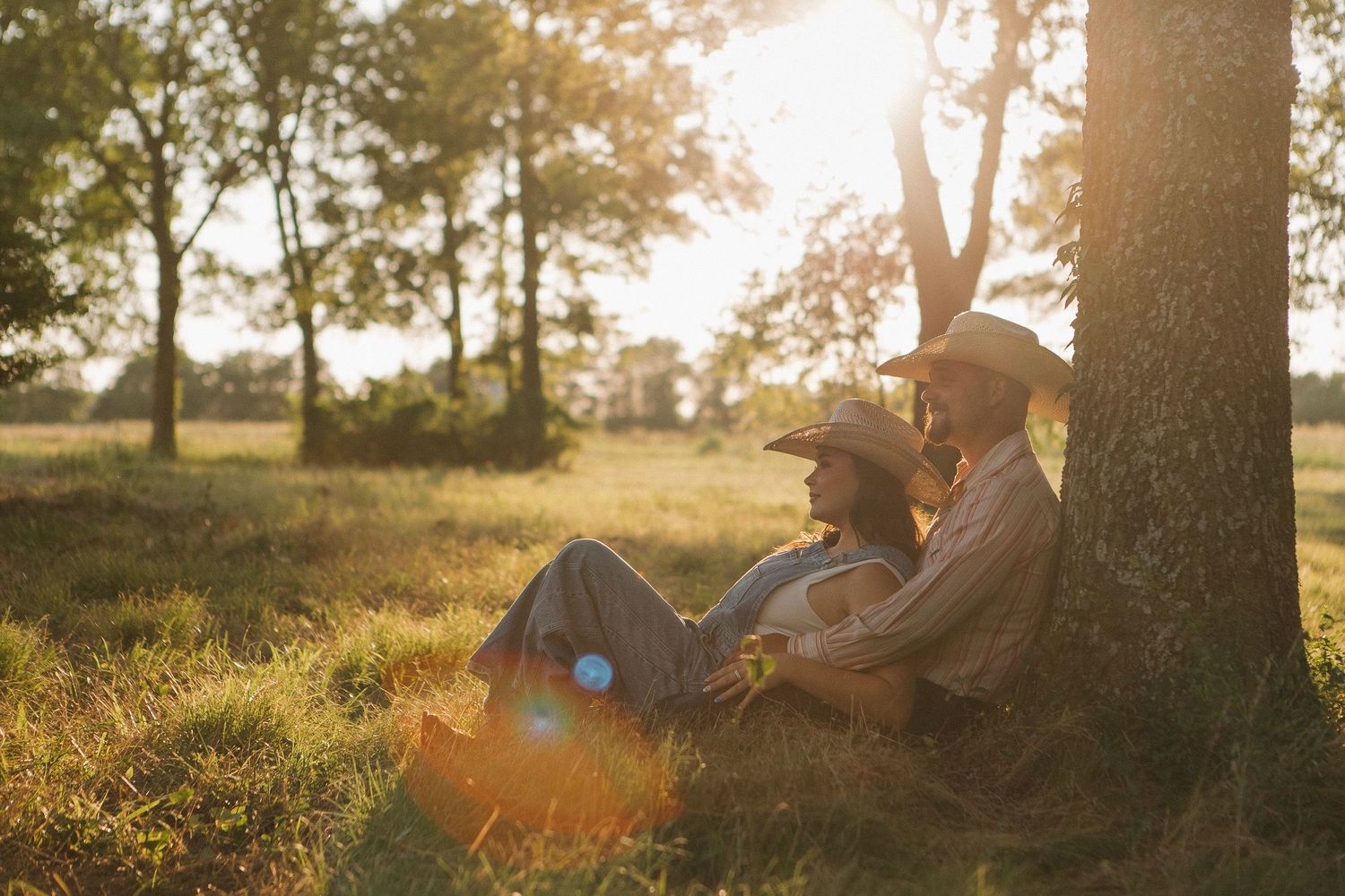 Silhouetted couple relaxing under trees during golden sunset hour.