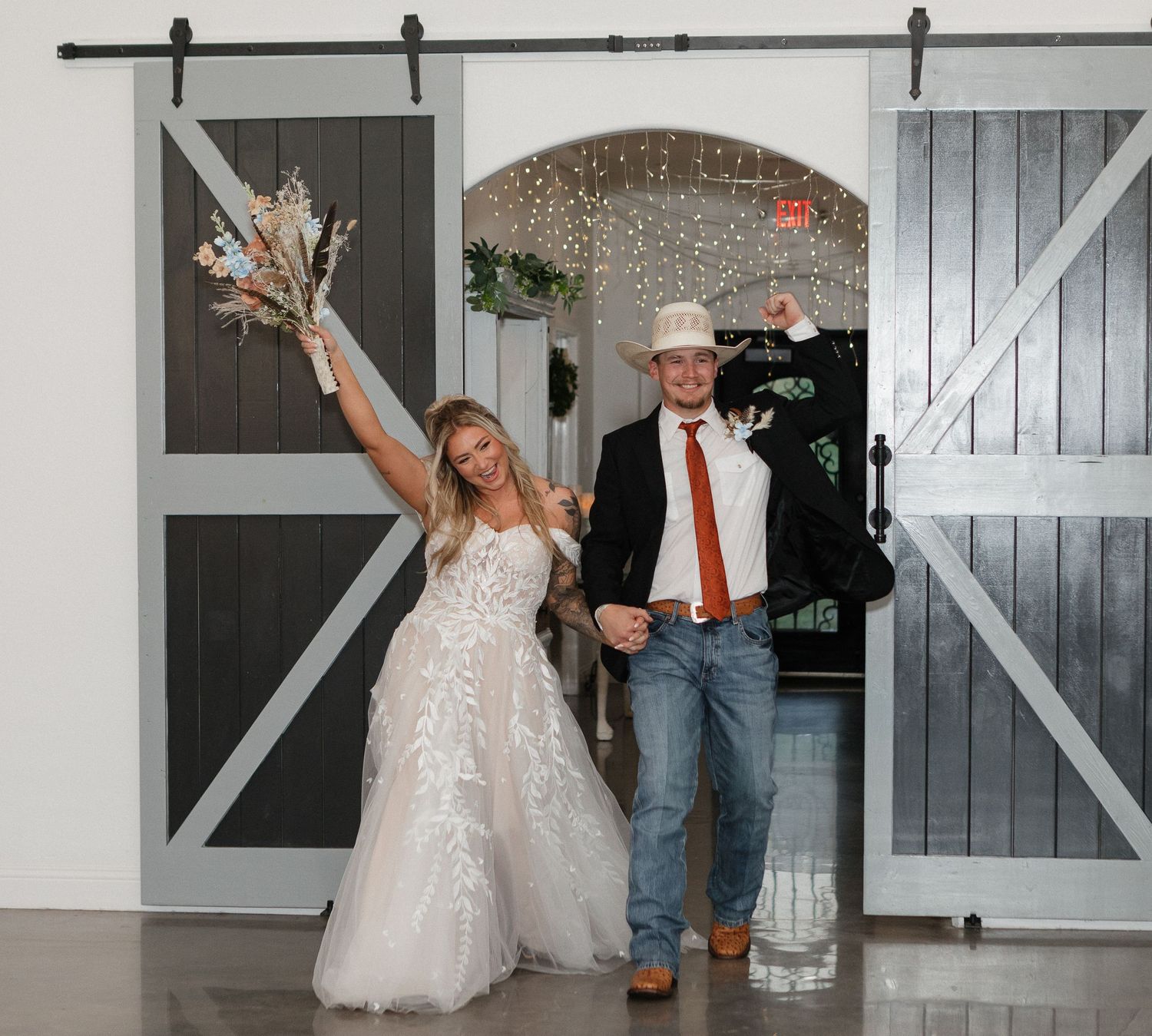Wedding couple dancing in rustic barn venue with sliding doors.