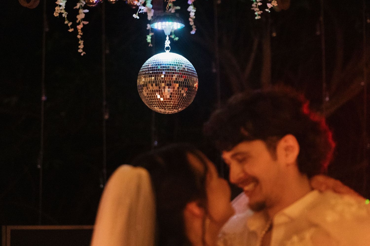 Couple sharing a romantic dance under a sparkling disco ball at an outdoor evening wedding reception. Caddo Mills Texas wedding photographer