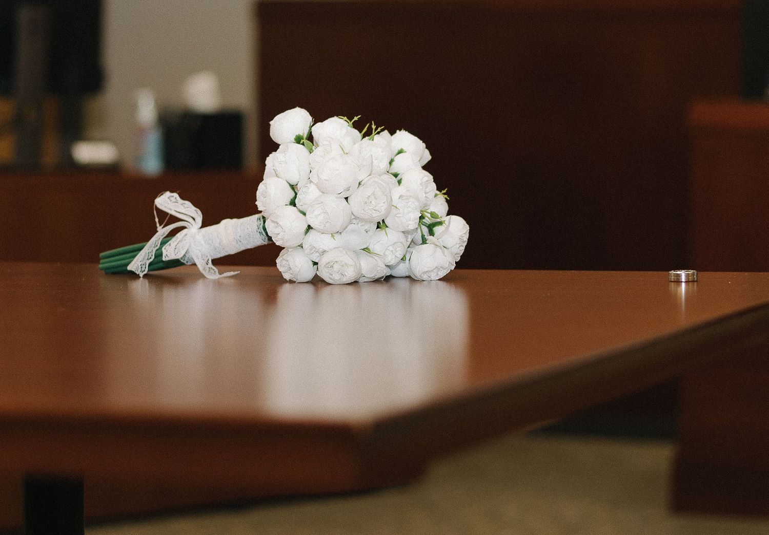 White tissue paper flowers arranged in a line on a dark wooden table surface in an indoor setting.
