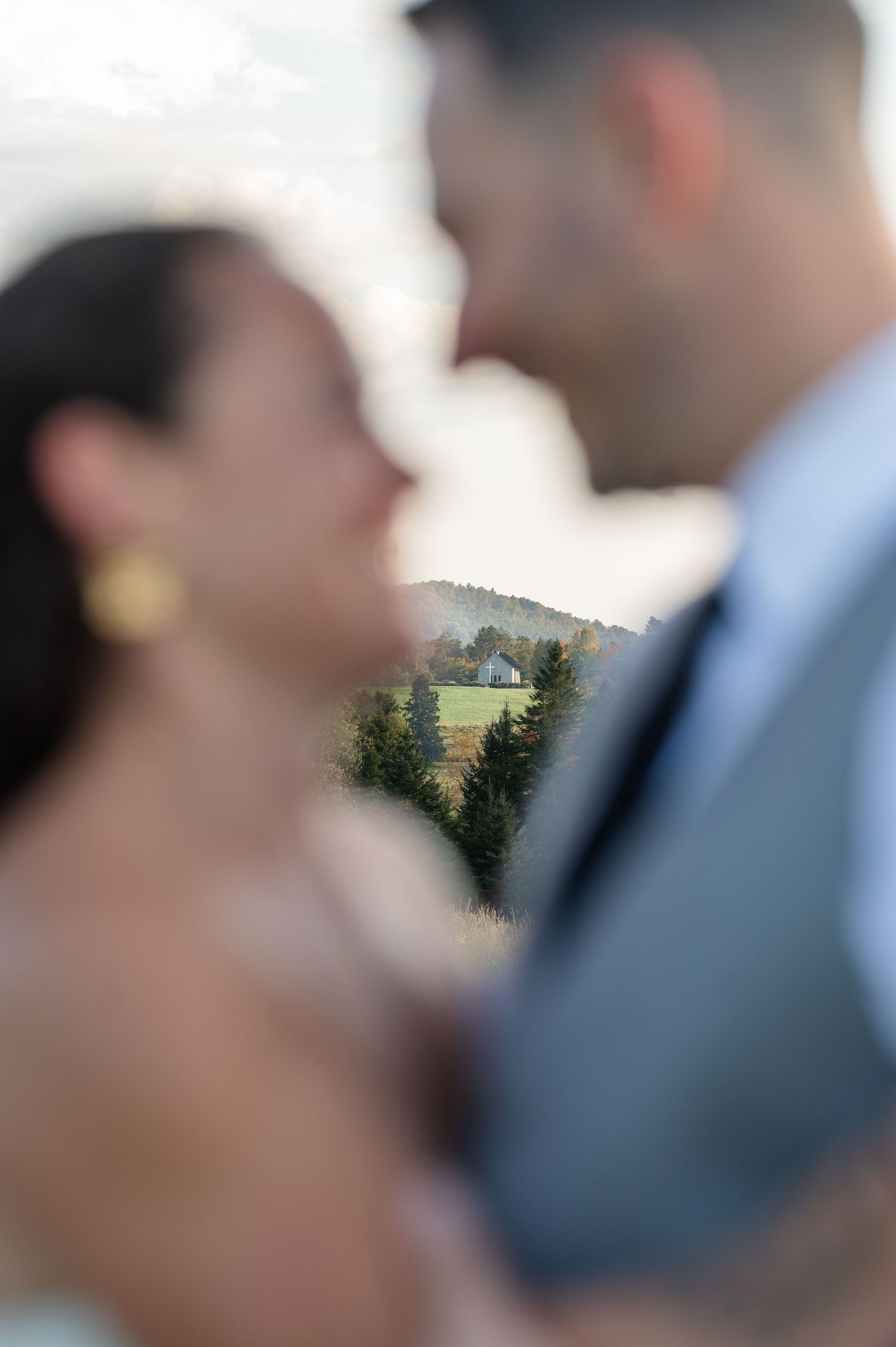 Romantic wedding couple portrait with scenic countryside background featuring rolling hills and evergreen trees.