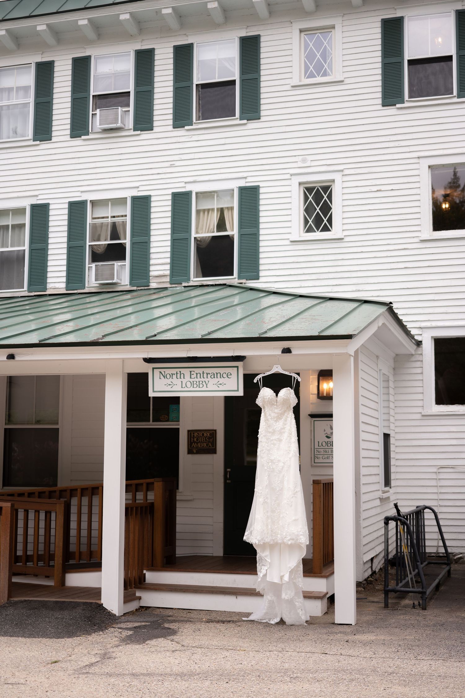 White wedding dress hanging at the North Entrance Lobby of a classic New England inn with green shutters.