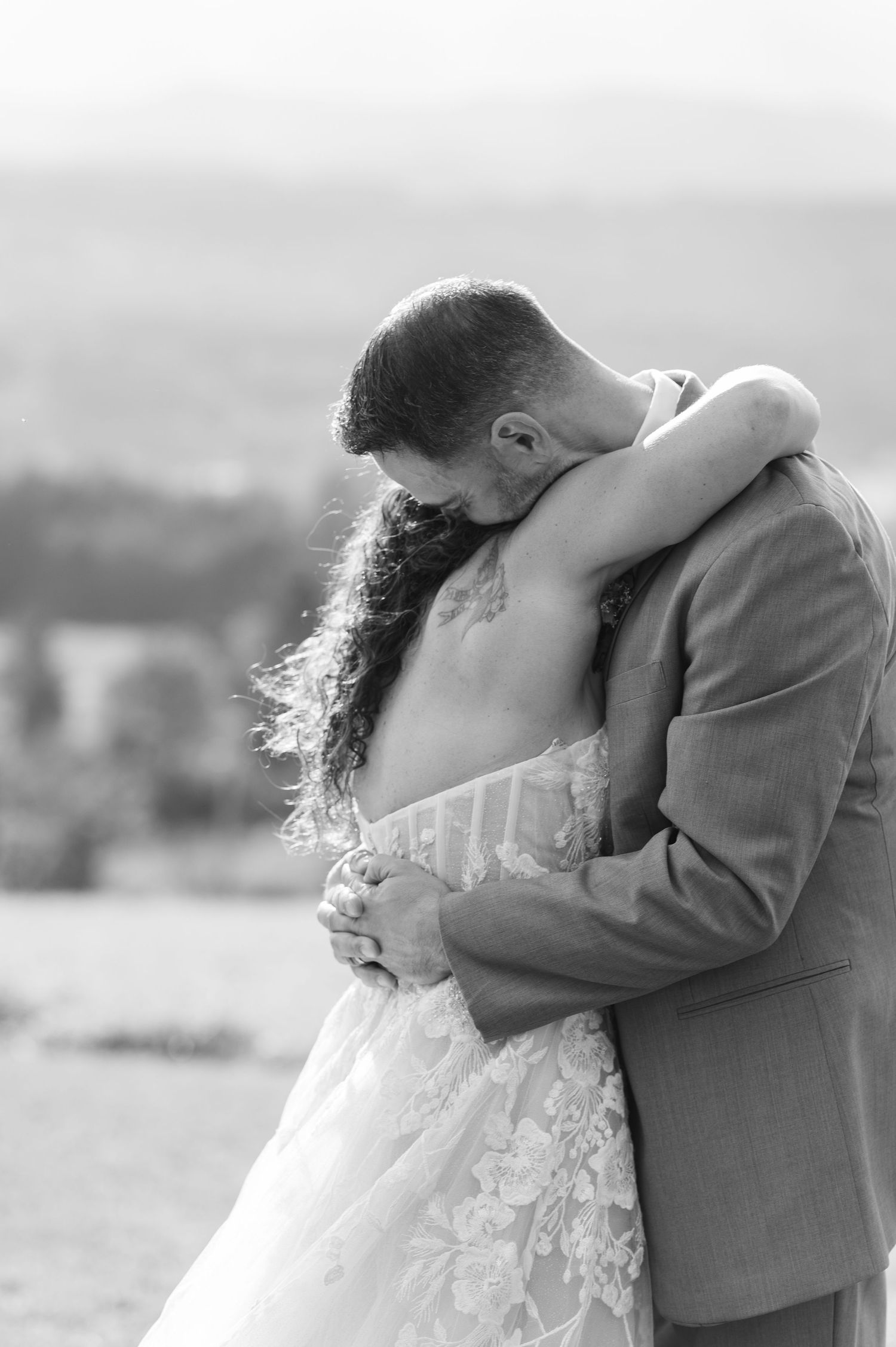 Black and white photo of bride and groom embracing tenderly on their wedding day.