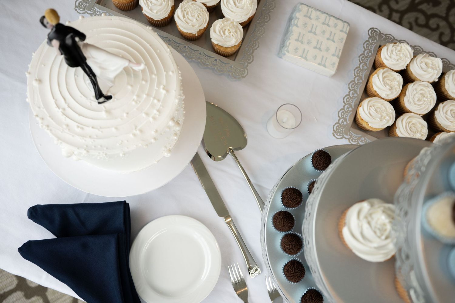 Aerial view of wedding dessert table with cake topper, cupcakes, and chocolates.