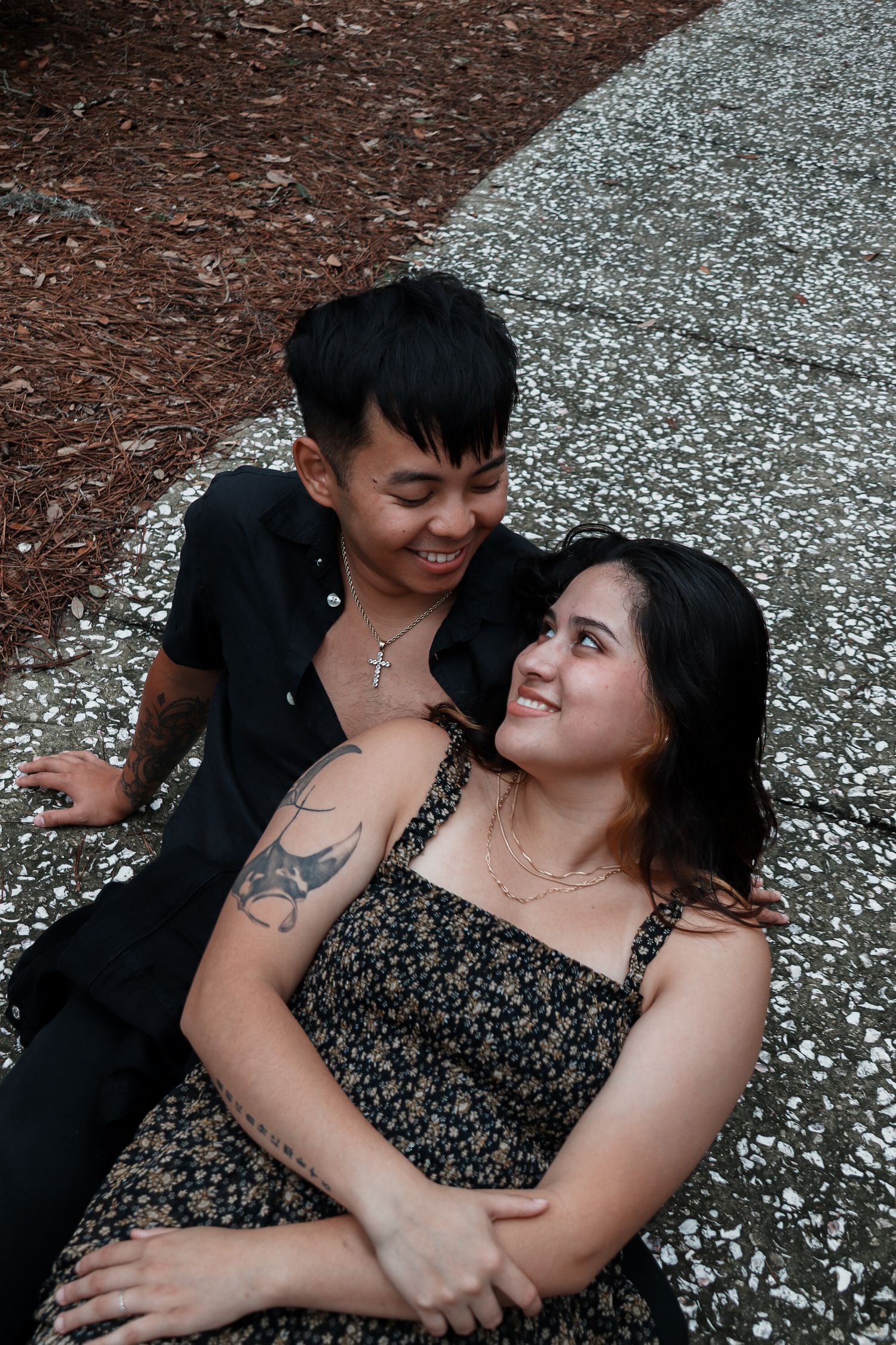 Couple lying on gravel ground sharing tender moment together.