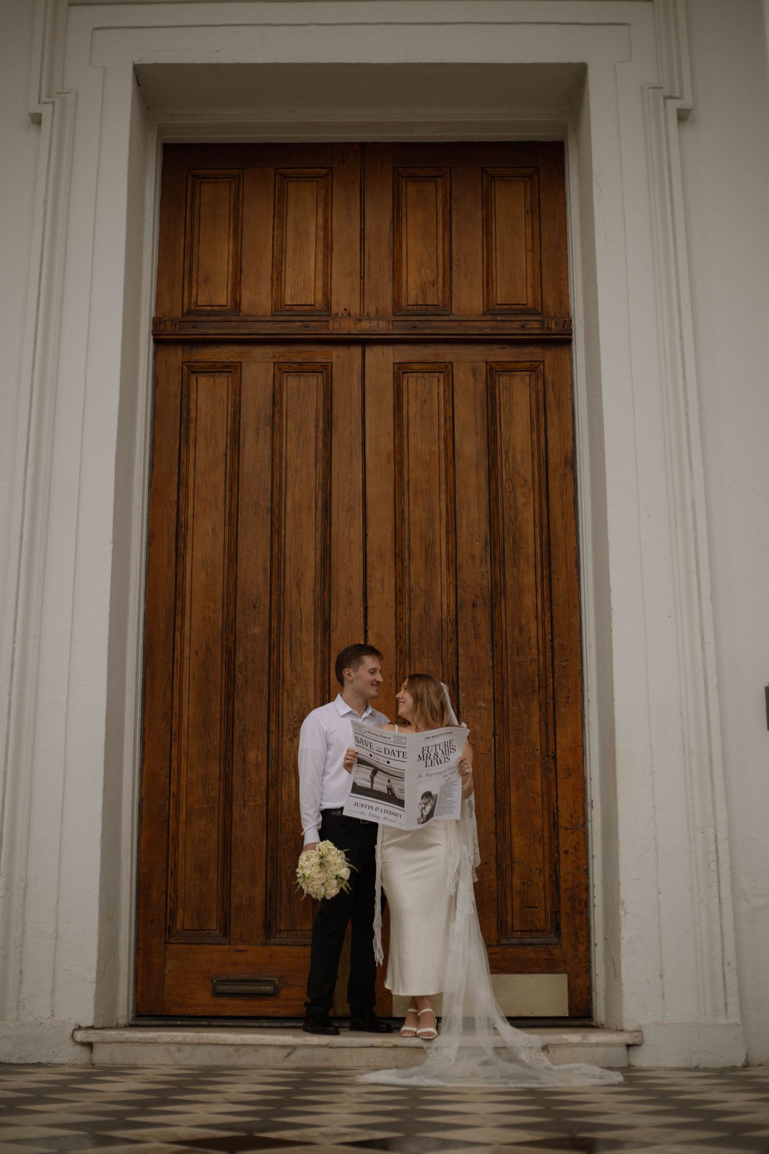 Elegant wedding couple shares intimate moments against grand wooden doors of historic building.